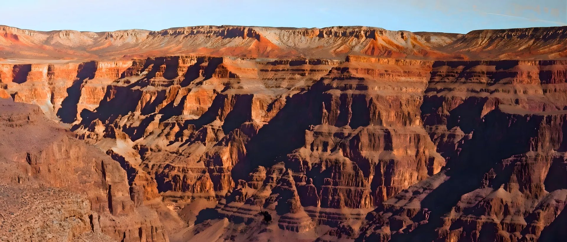Cinematic wide shot of a black helicopter flying low through the Grand Canyon filming for Soarin Across America.