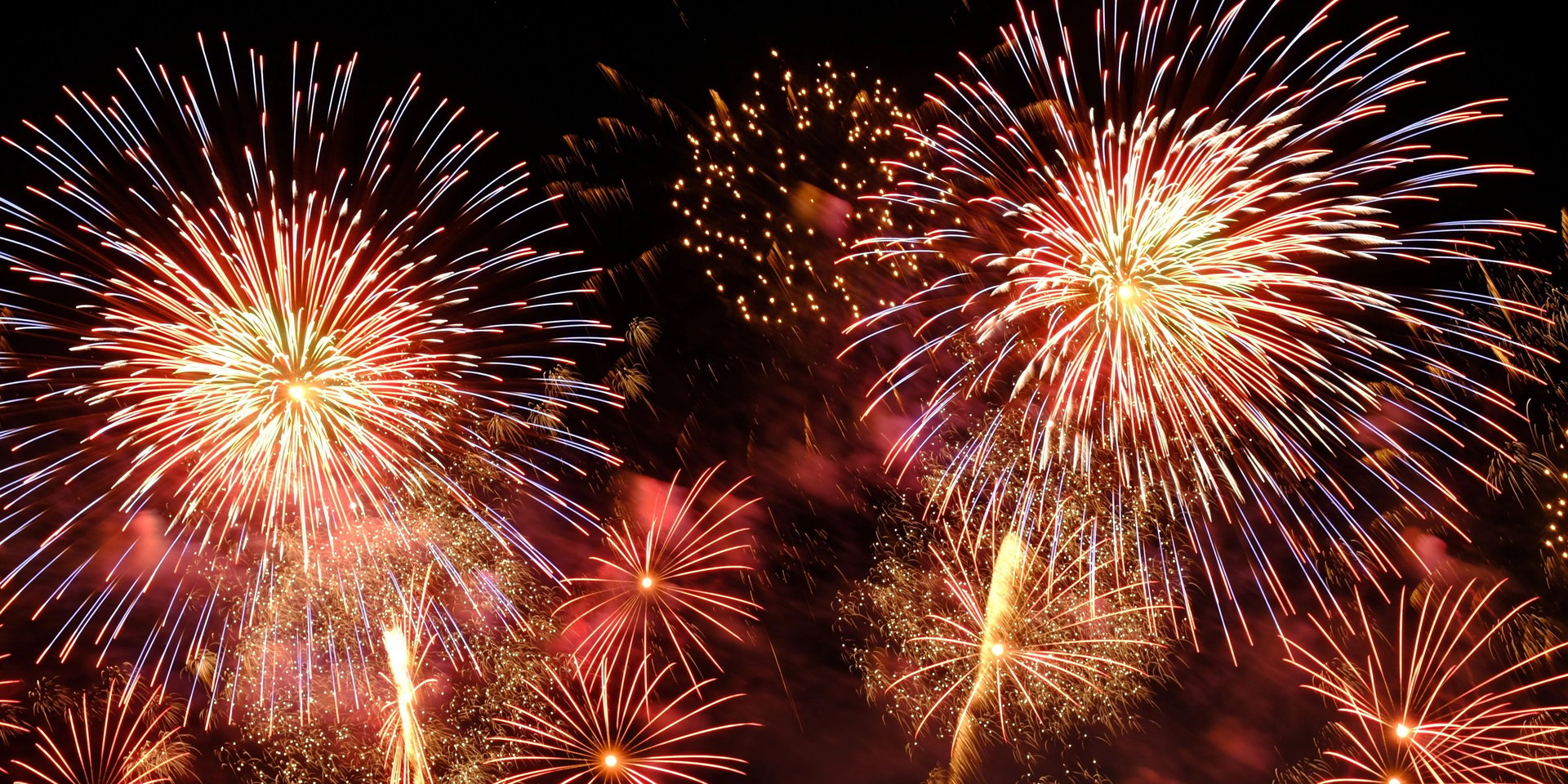 A massive, brightly colored 4th of July fireworks display exploding in the night sky