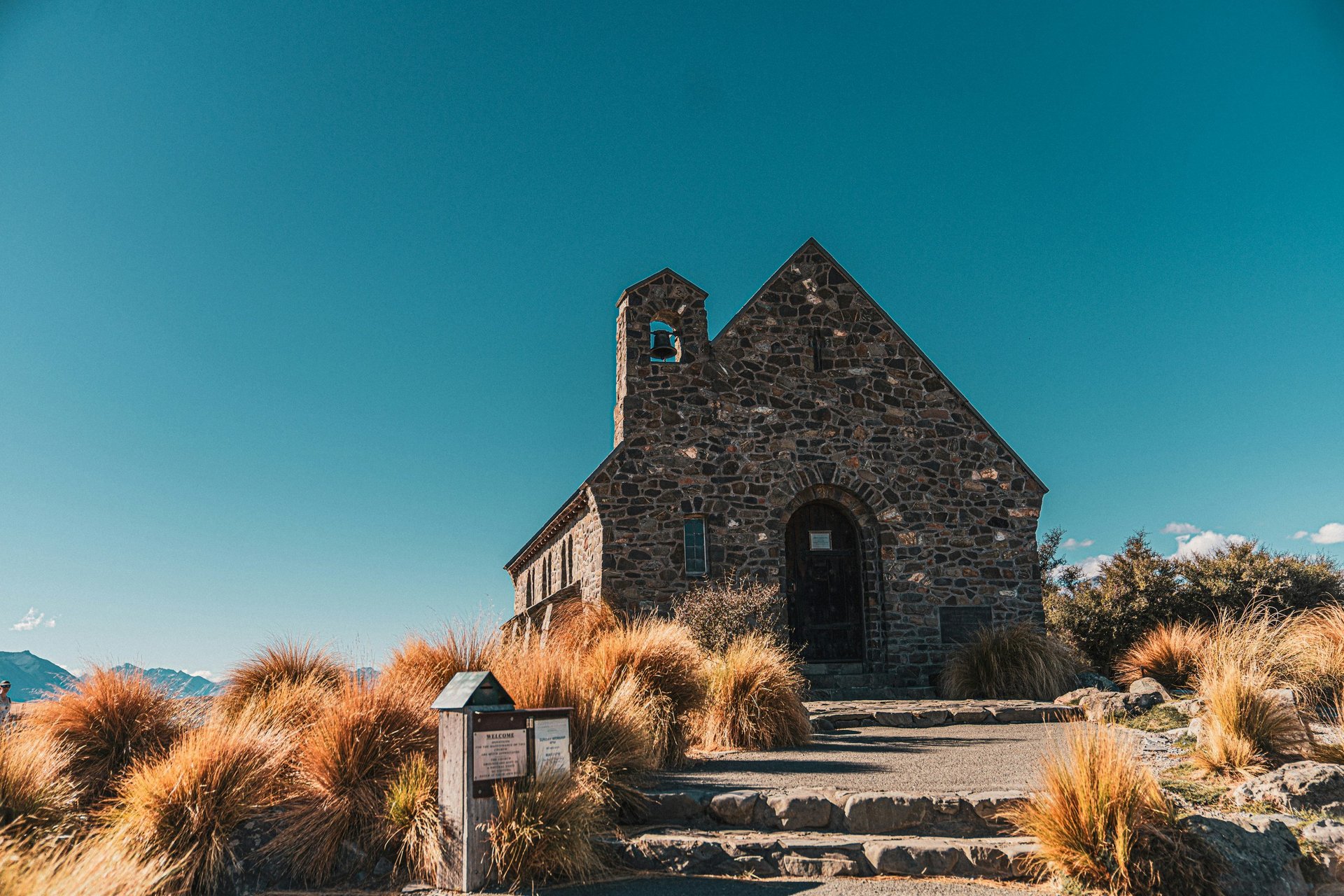 white and brown house near green grass field and body of water during daytime