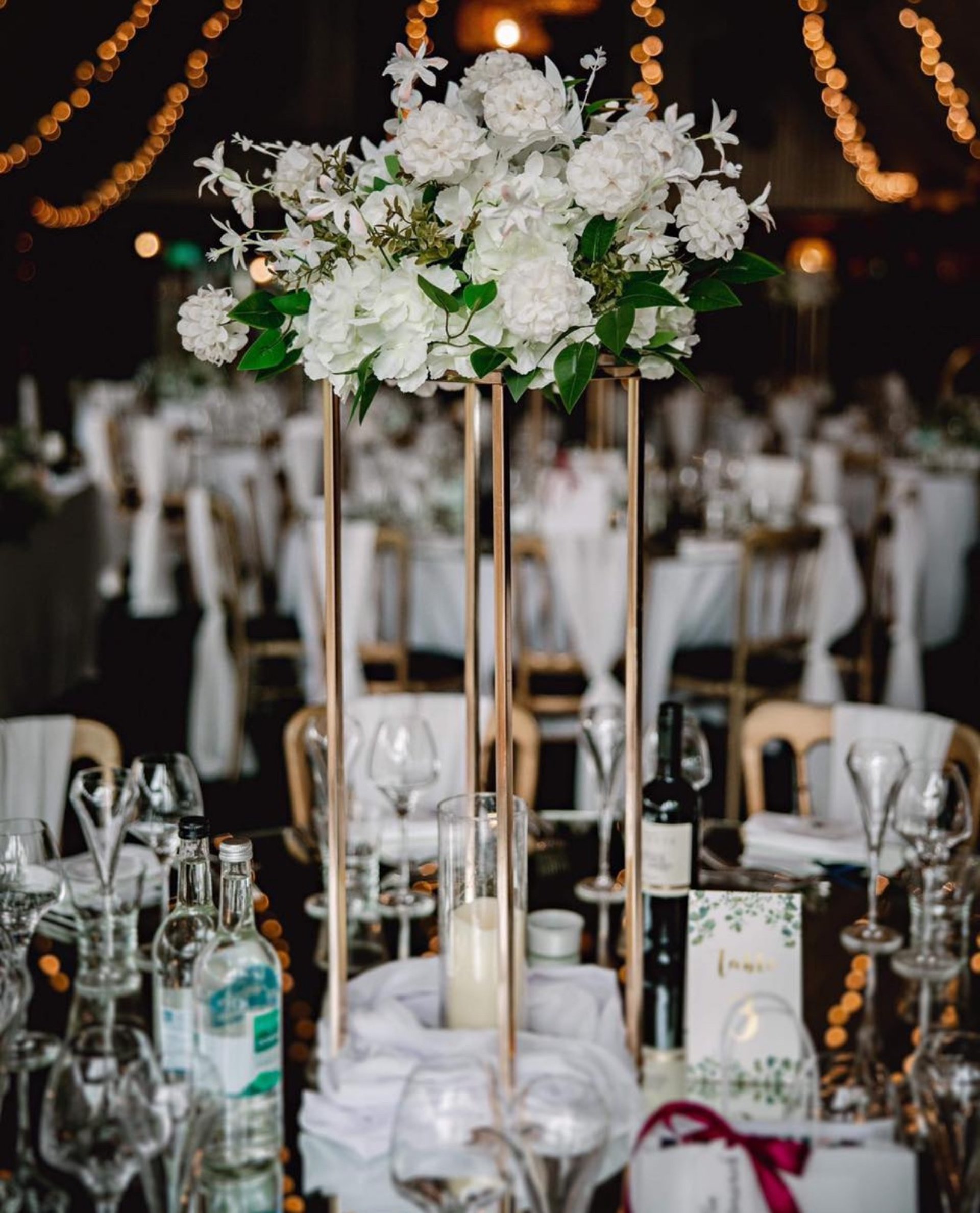 a table set with white flowers and greenery