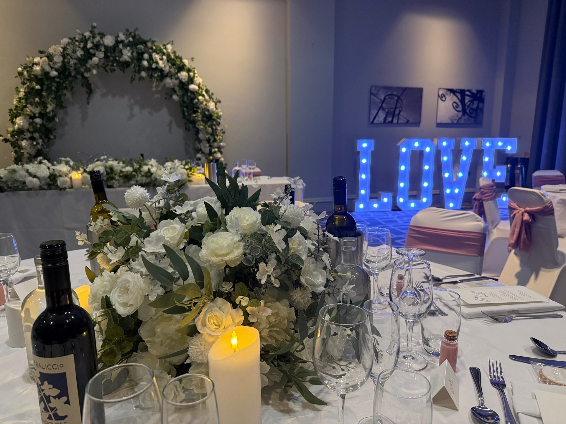 a table set with white flowers and greenery