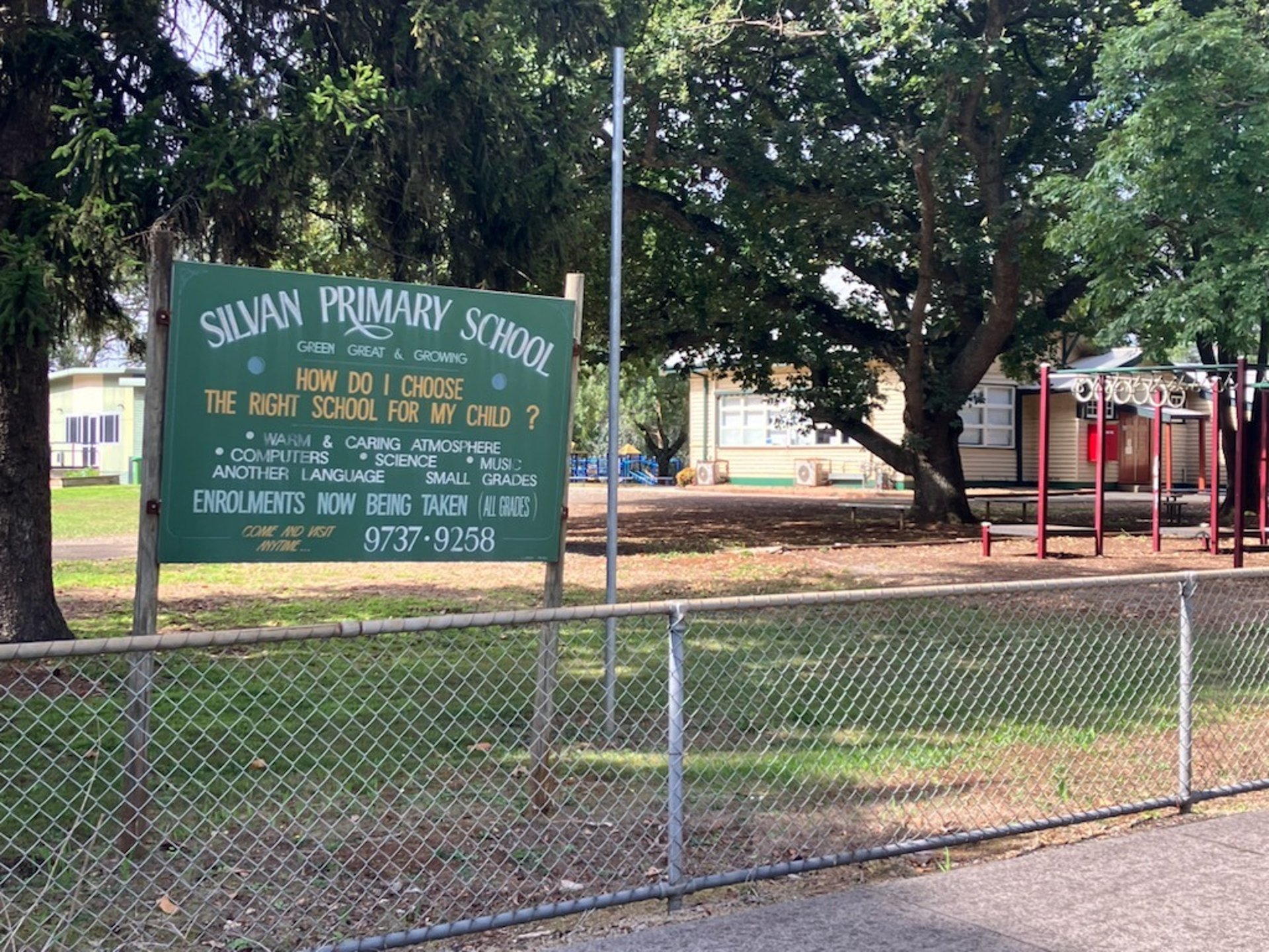 Silvan primary school with a green sign with white writing Silvan Primary School the school is in the background