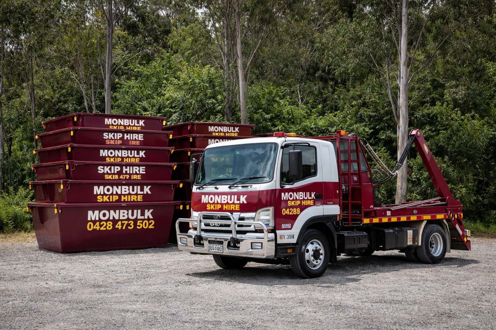 maroon skip bins stacked in piles with Monbulk Skip Hire delivery truck park with trees at the back
