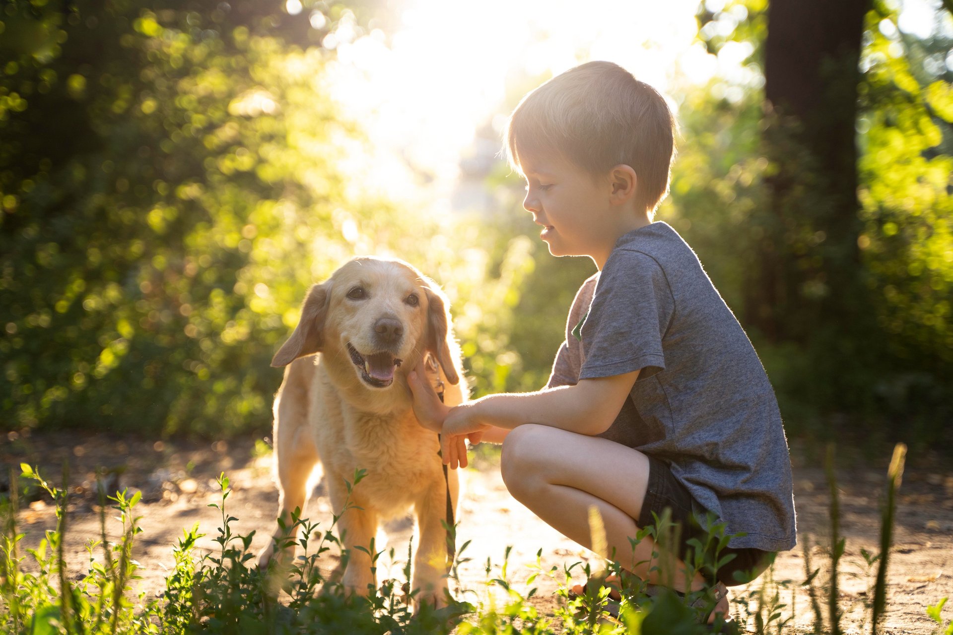 Two girls sitting in the grass with a dog
