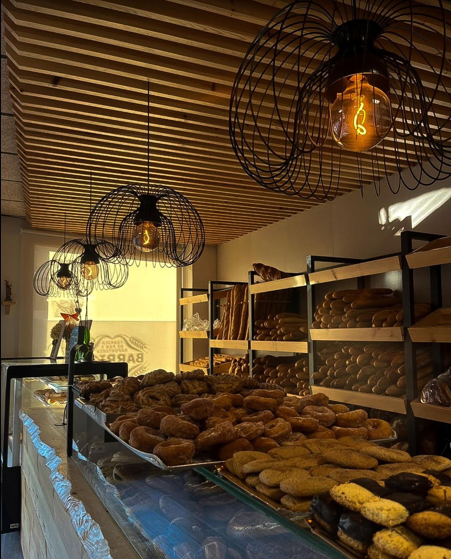 man in white dress shirt standing in front of brown wooden shelf
