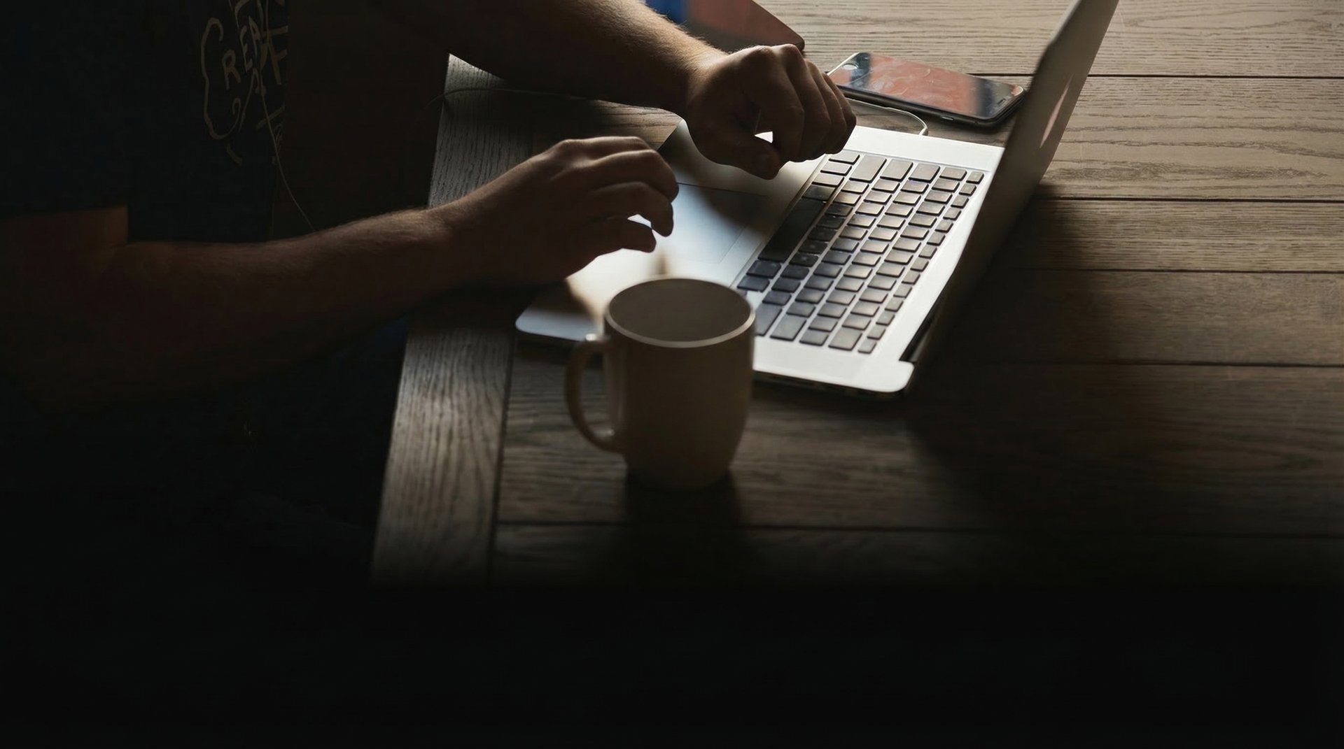 gray laptop computer on brown wooden table beside person sitting on chair