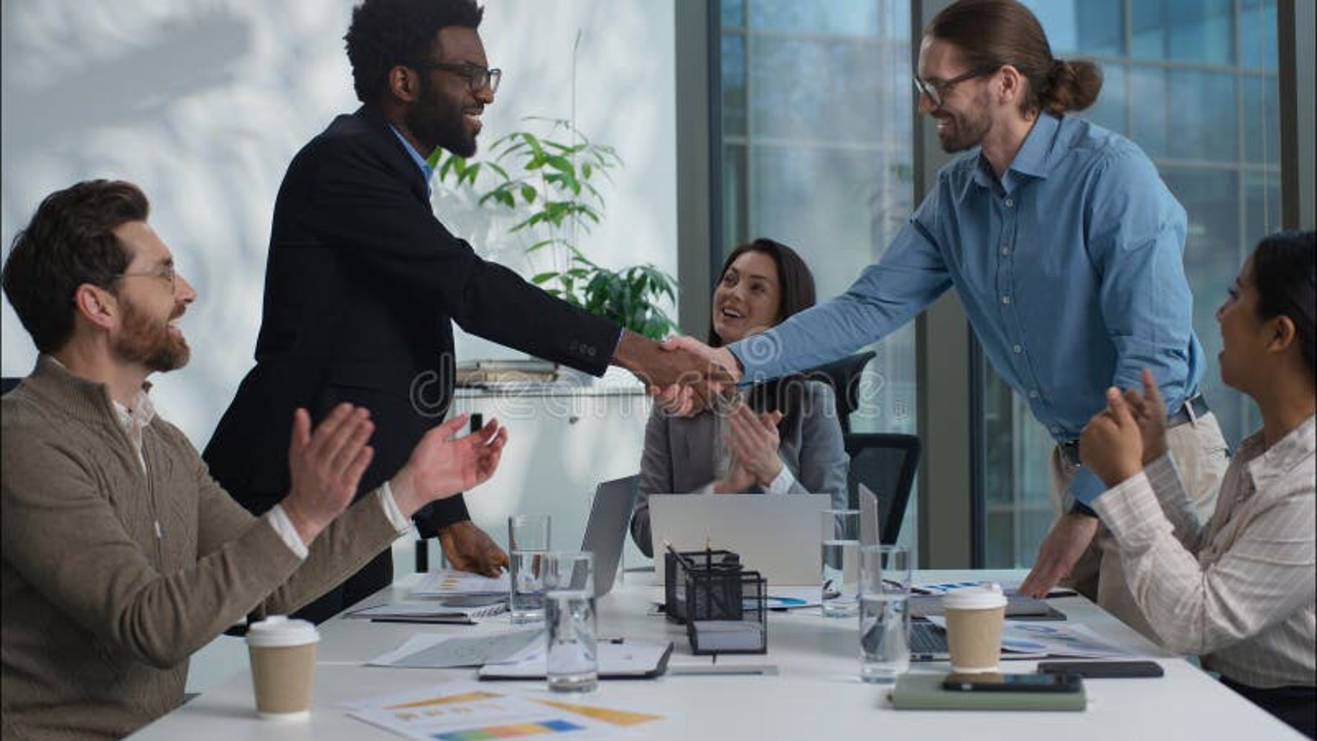 a woman standing at a desk in front of a laptop computer