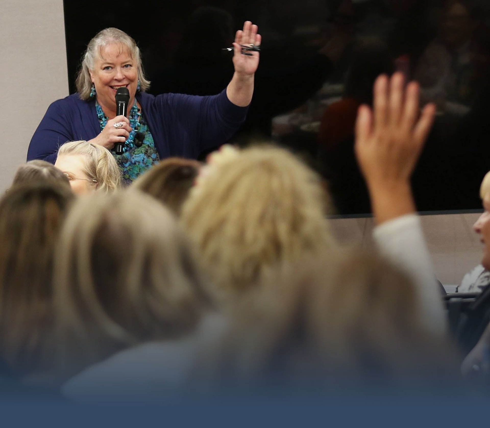 Debbie Chen speaking with a microphone to an engaged audience, Business Leadership Coach and speaker.