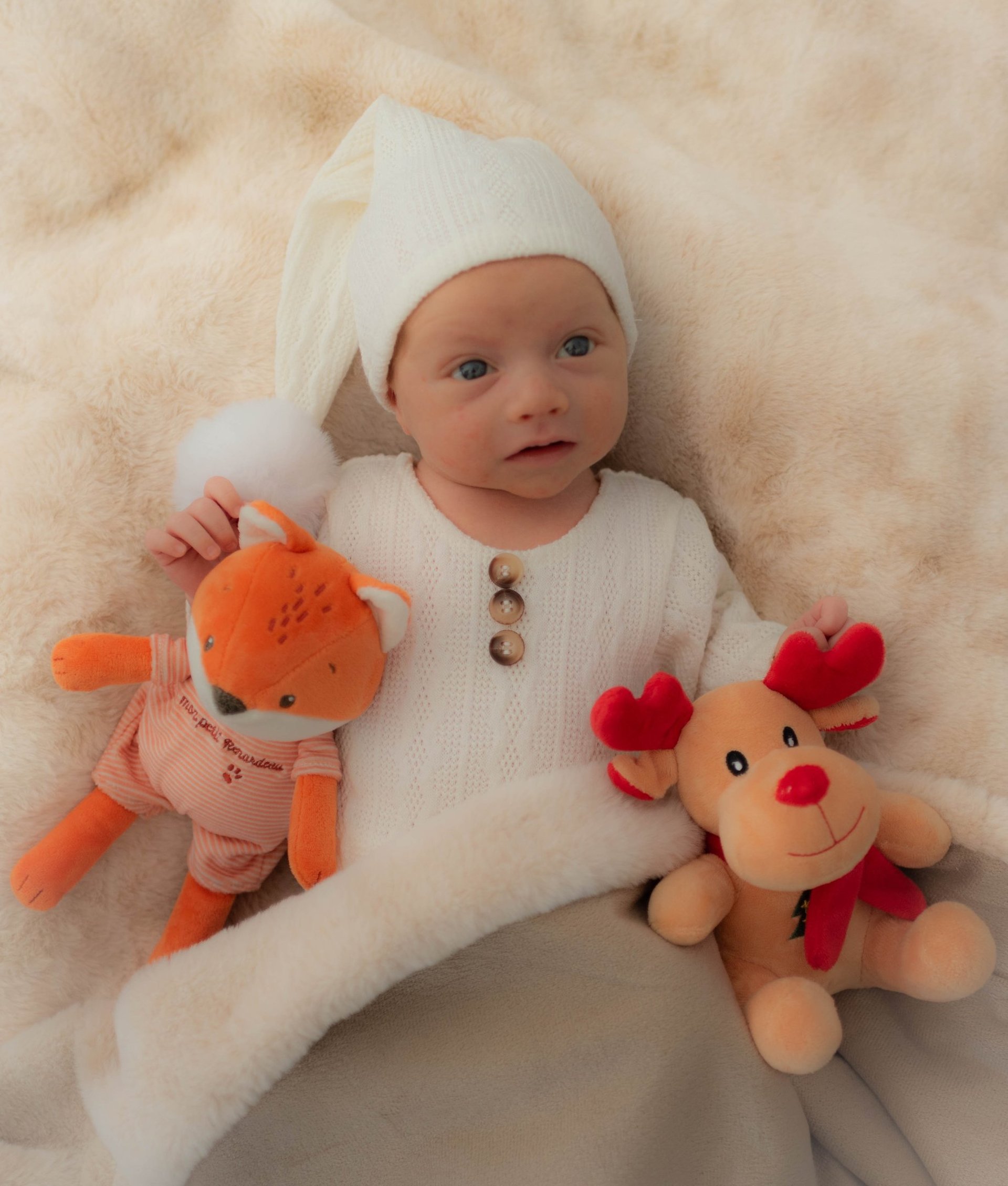 Nourrisson entouré de ses doudous dans son lit douillé