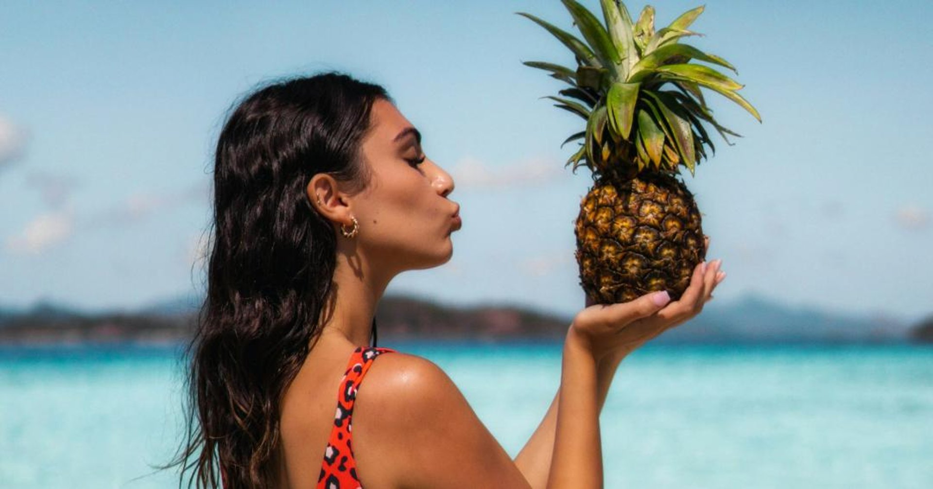 Woman on beach holding pineapple