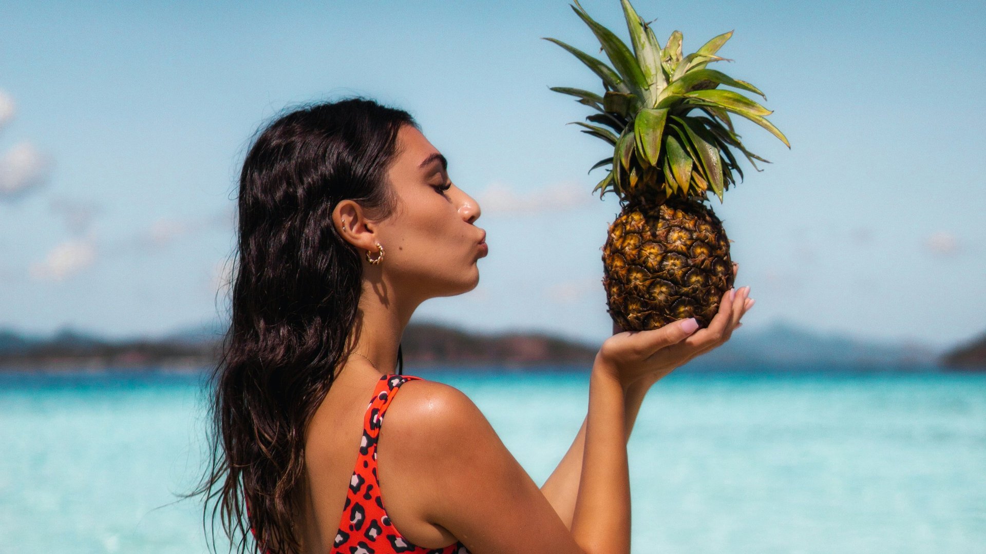 Woman on beach holding pineapple