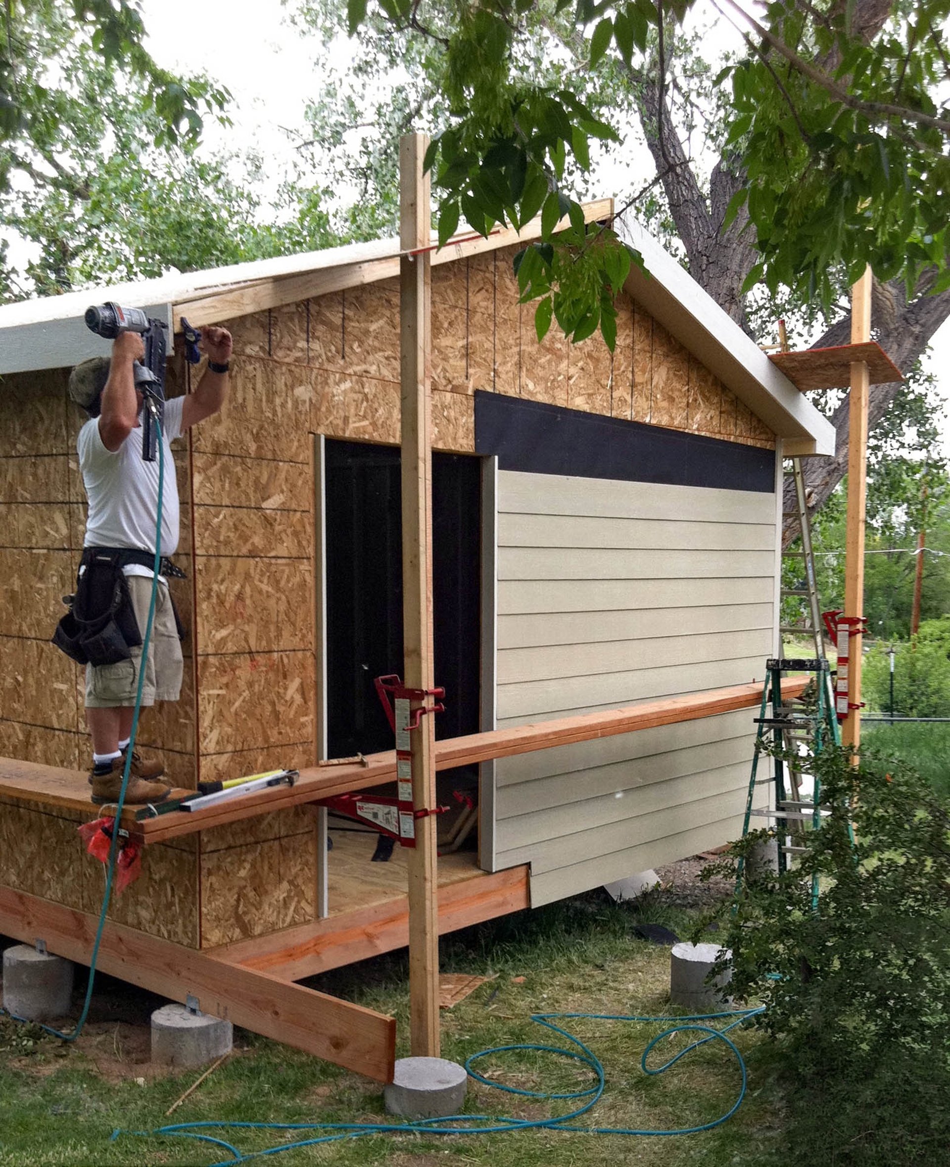 Brewer Construction installer mounting vinyl siding on a custom storage shed in Denver, CO.