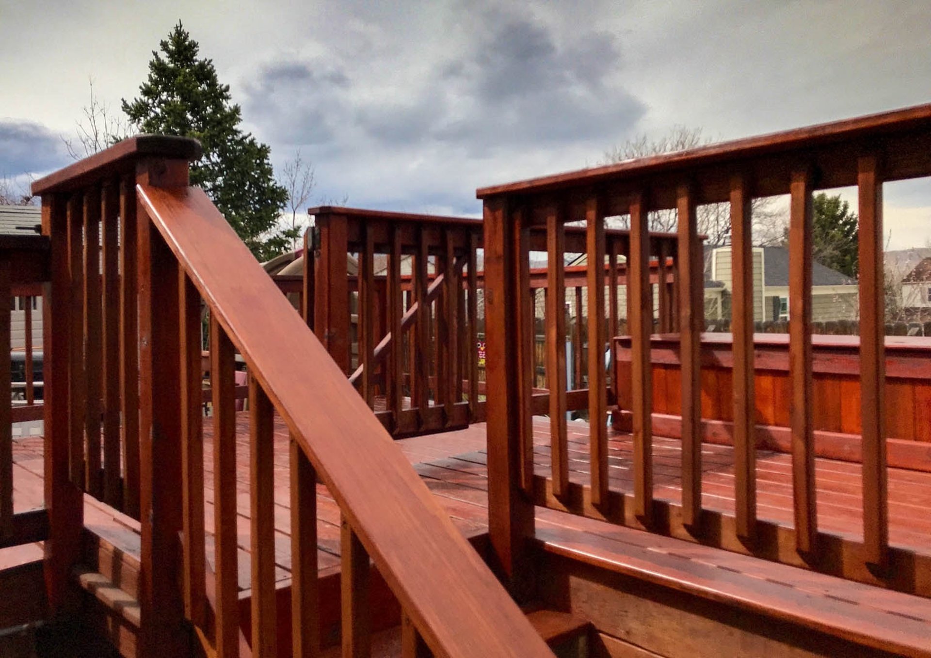 Close-up view of a custom-built red-brown deck railing and stairs by Brewer Construction in a Lakewood home.