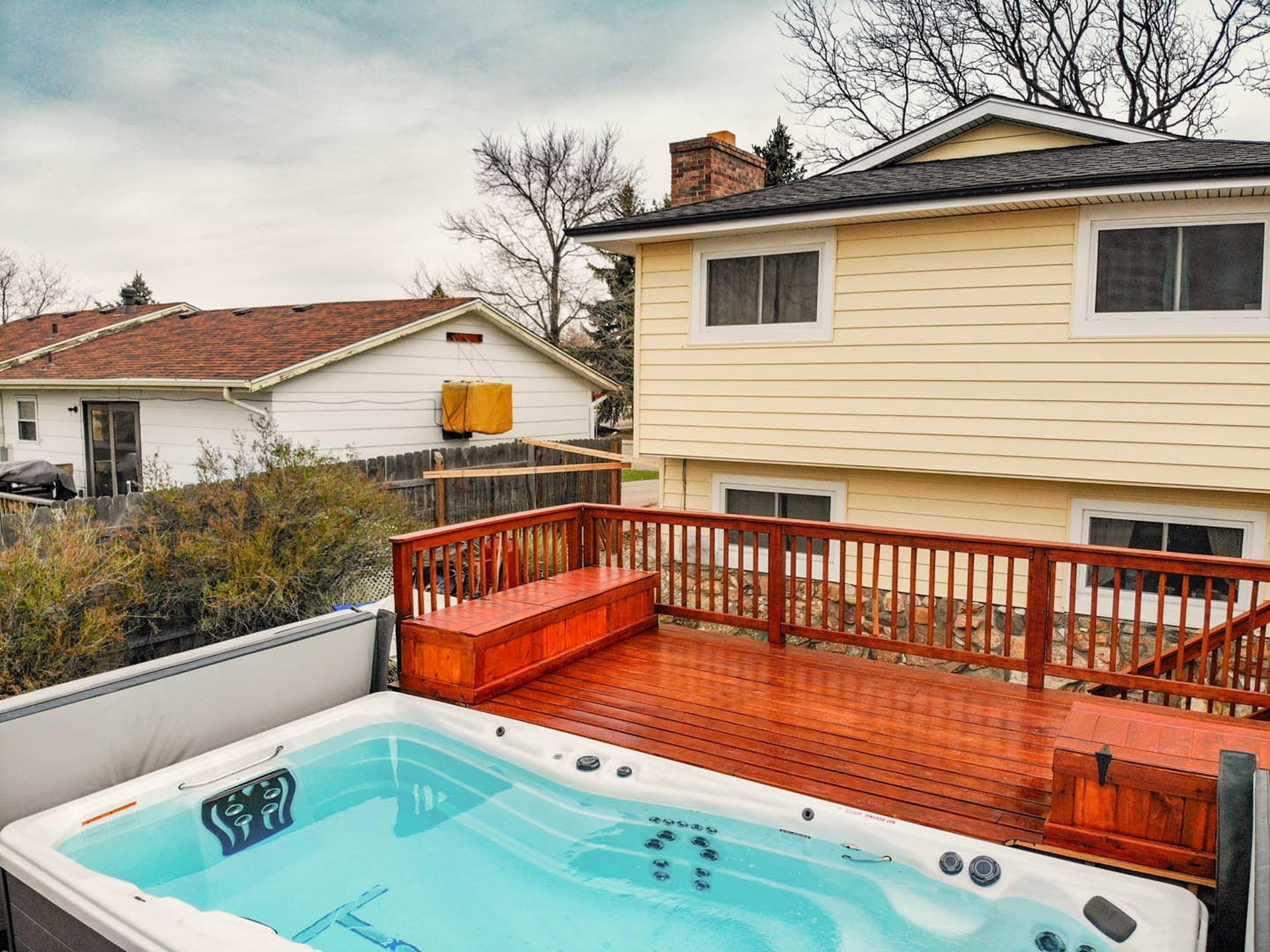 Elevated view of a completed custom Brewer Construction deck with a hot tub attached to a Lakewood house.