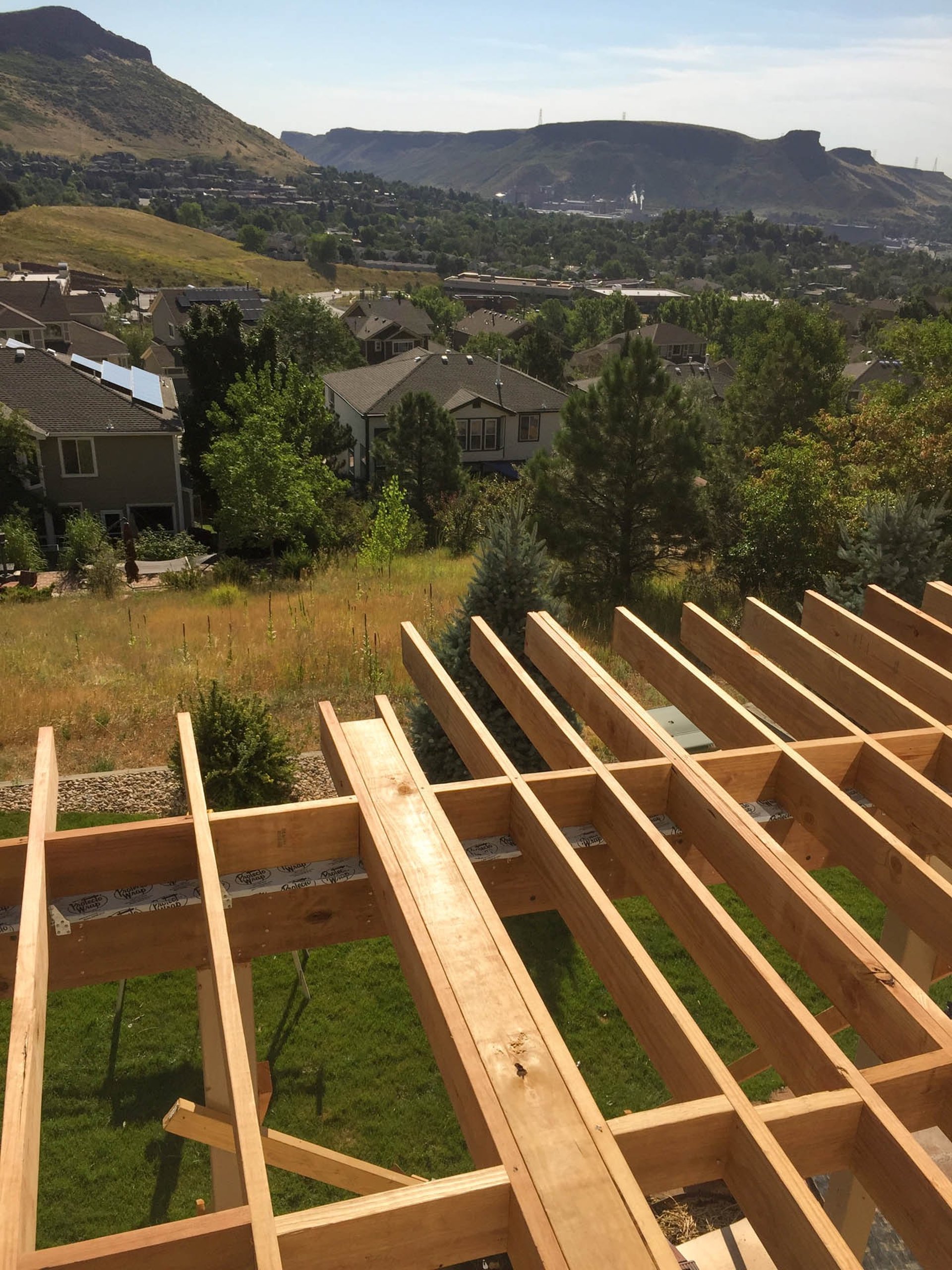 Overhead look at structural wood deck joists and framing overlooking a valley in Golden, Colorado.