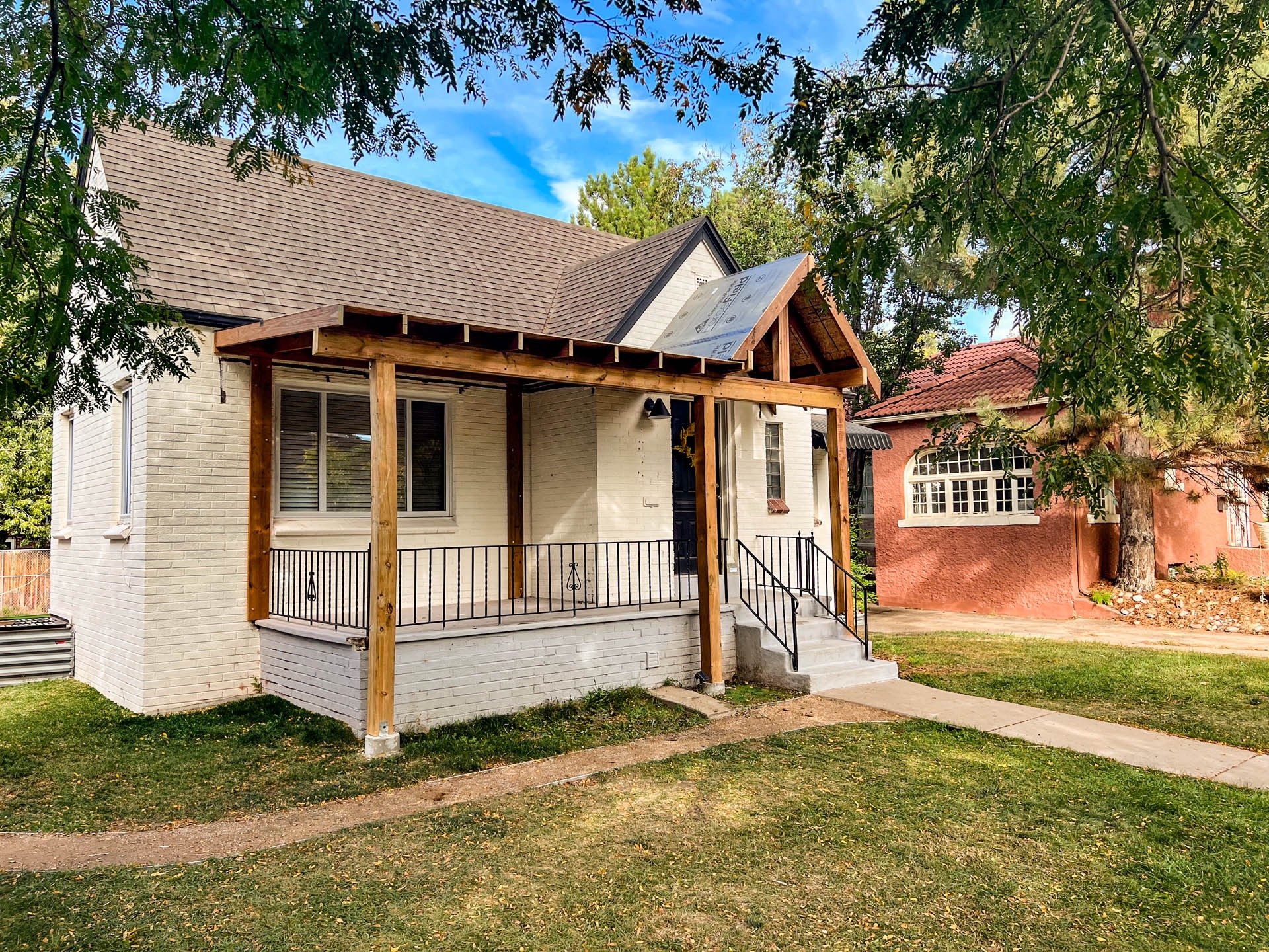 Finished covered front porch with custom wood post framing on a white brick house in Genesee.
