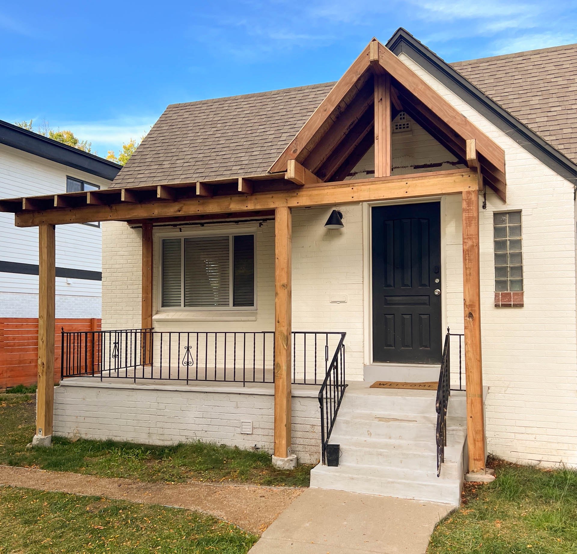 Completed front entry porch remodel with natural wood pillars and steps by Dennis Brewer Construction.
