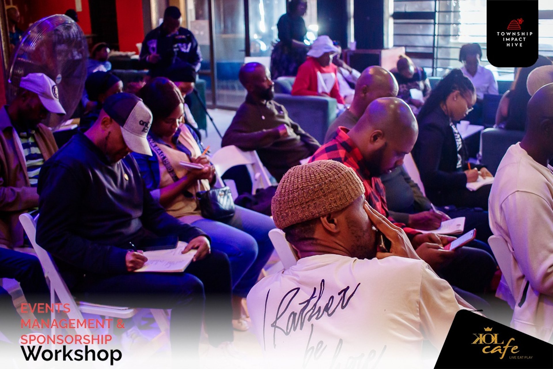 person discussing while standing in front of a large screen in front of people inside dim-lighted room