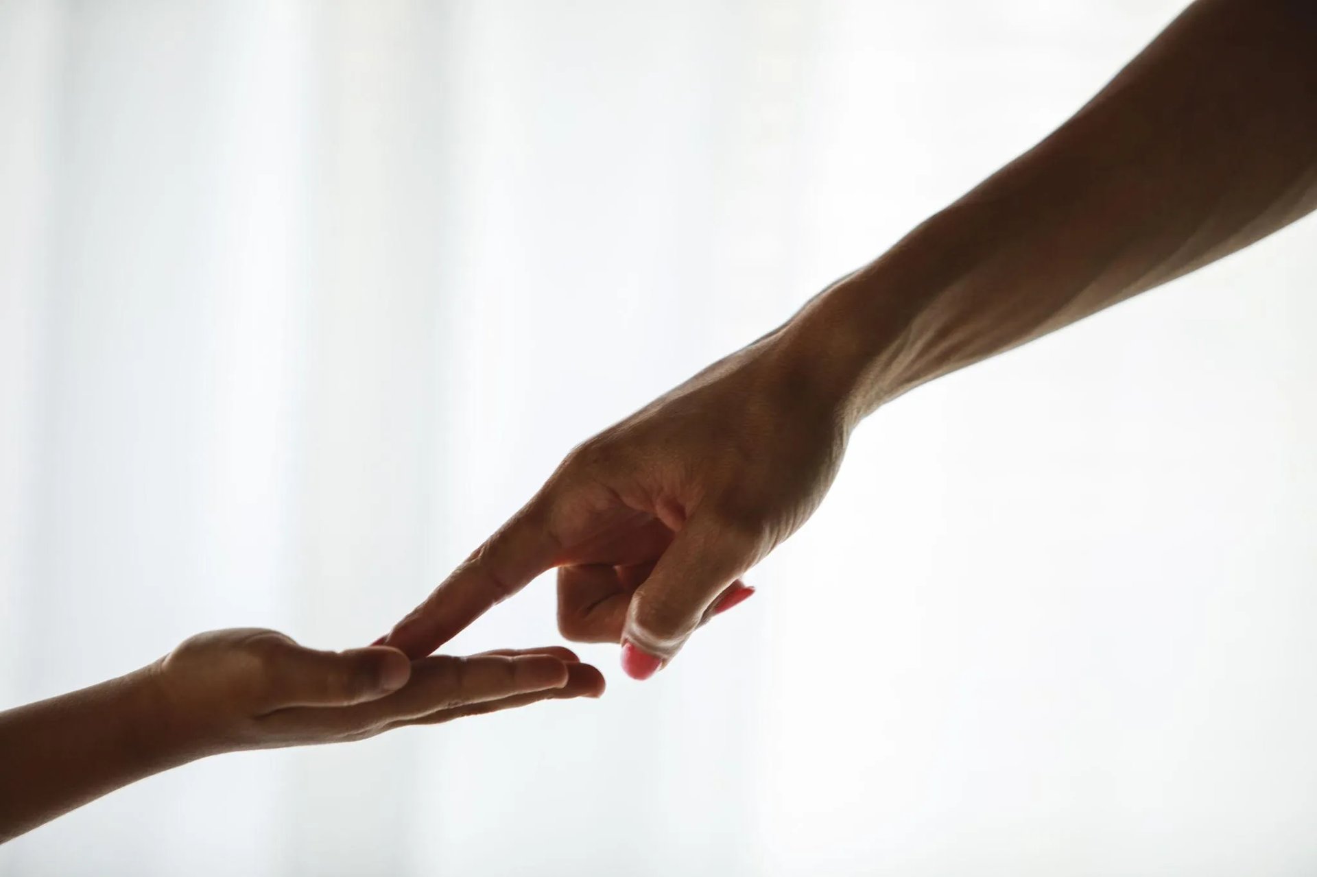 Une main tendue vers une autre, les doigts se touchant dans un geste de soutien.