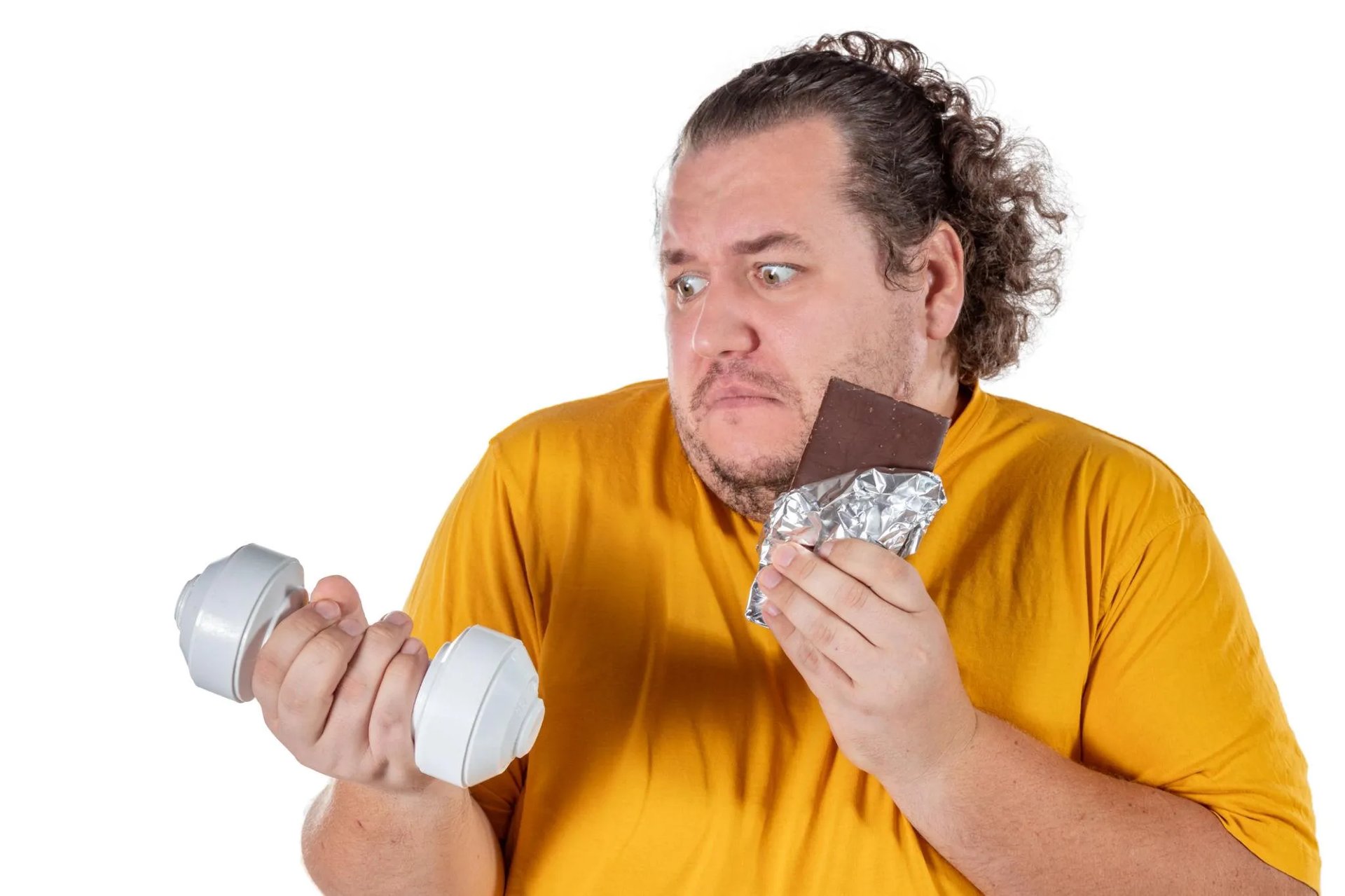 Homme en surpoids tenant un haltère et une tablette de chocolat, regardant hésitant entre les deux.