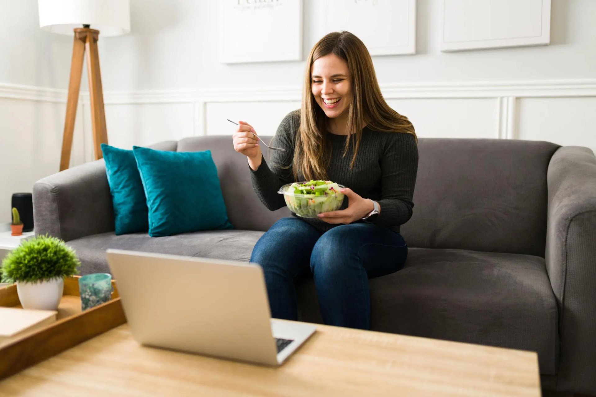 Femme mangeant une salade devant un ordinateur en suivi nutrition en ligne