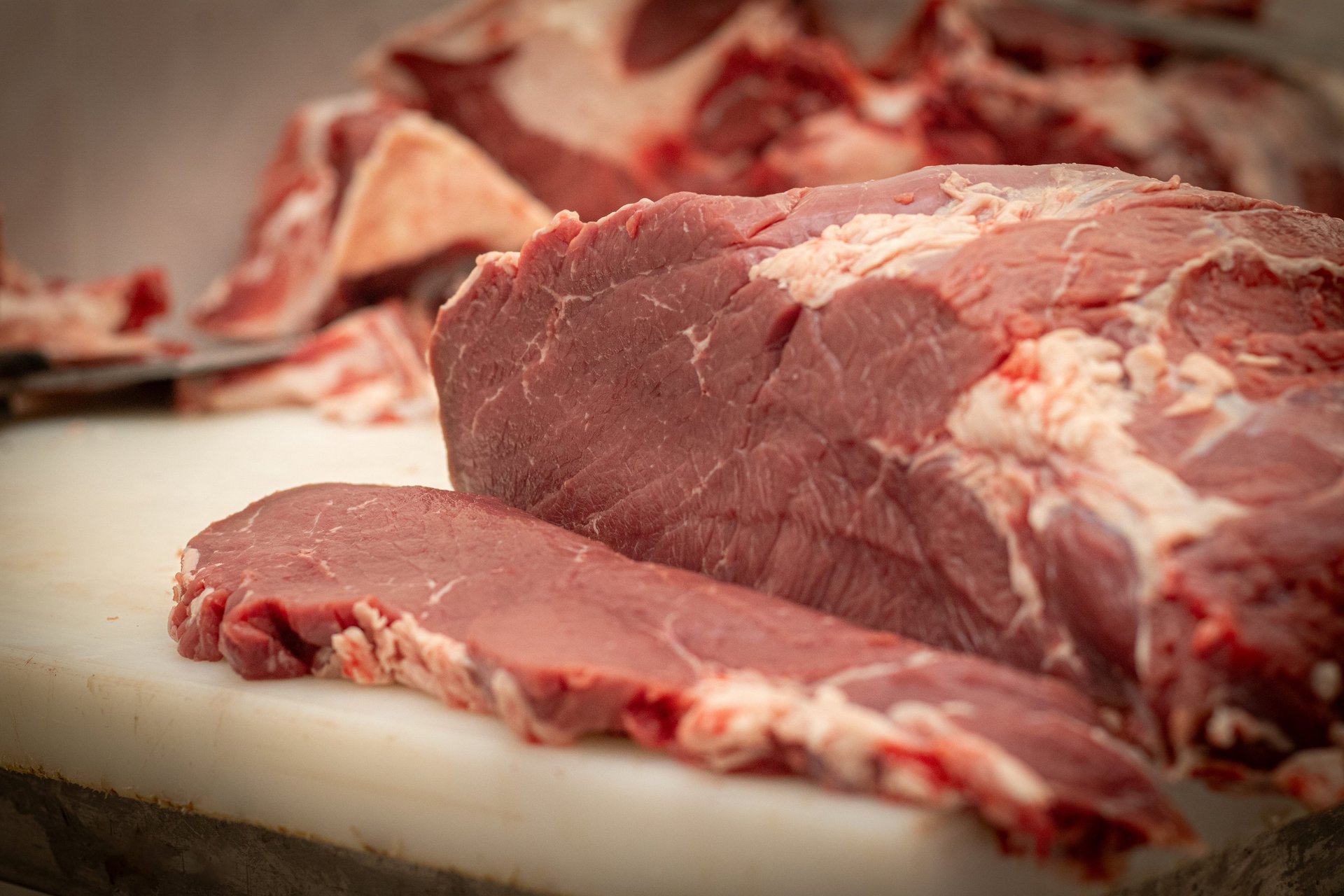 two steaks on a cutting board next to garlic, garlic, and a knife