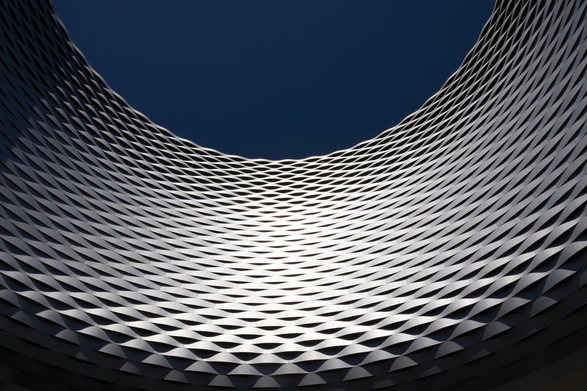 an abstract photo of a curved building with a blue sky in the background