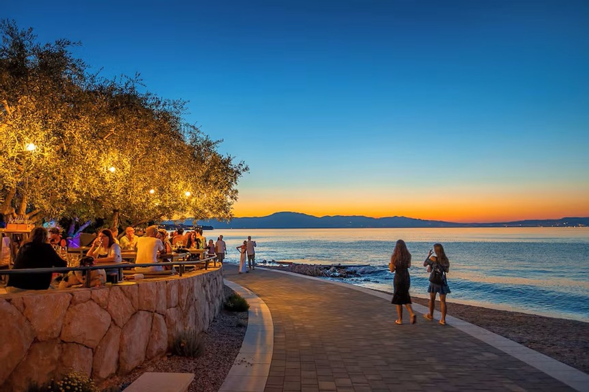 Strandpromenade von Rova bei Sonnenuntergang mit Restaurants