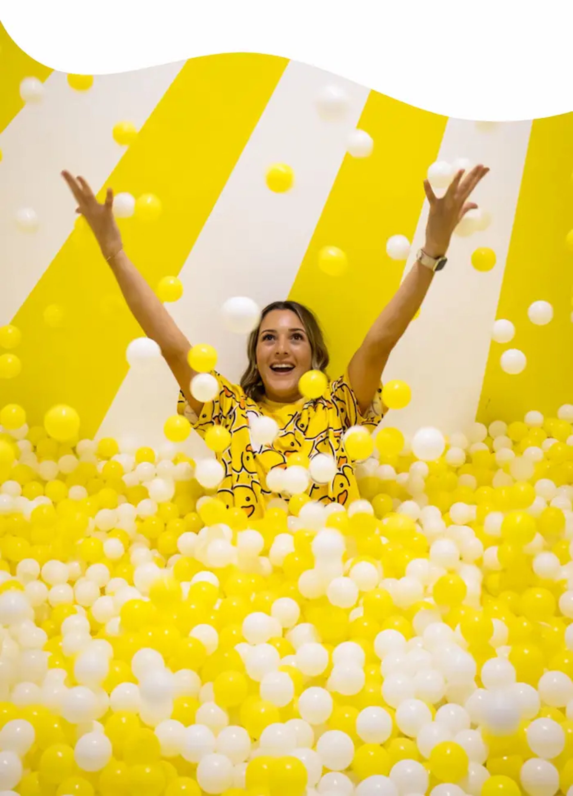 Woman enjoying a yellow ball pit at Selfie Experience Split – playful indoor activity in Split Old Town