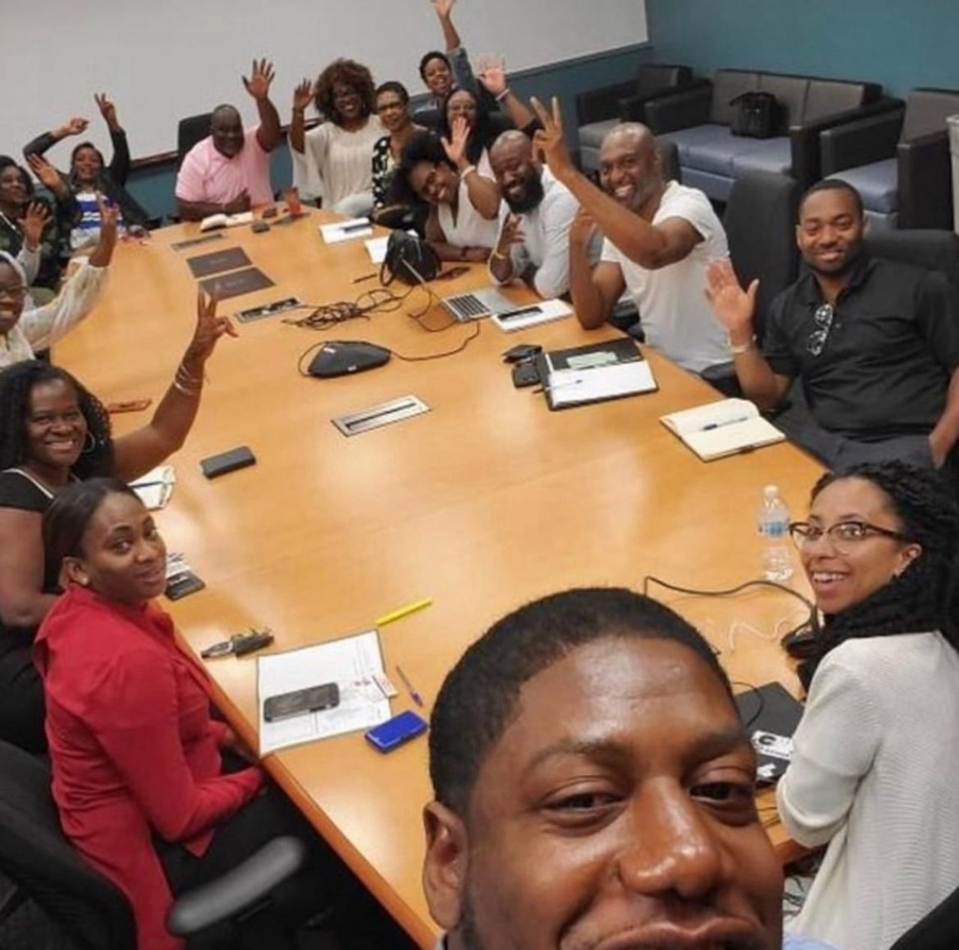 group of people sitting beside rectangular wooden table with laptops