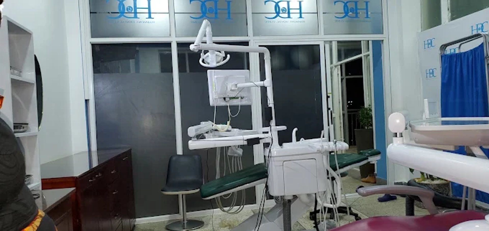 grayscale photo of woman using laptop near three salon chairs