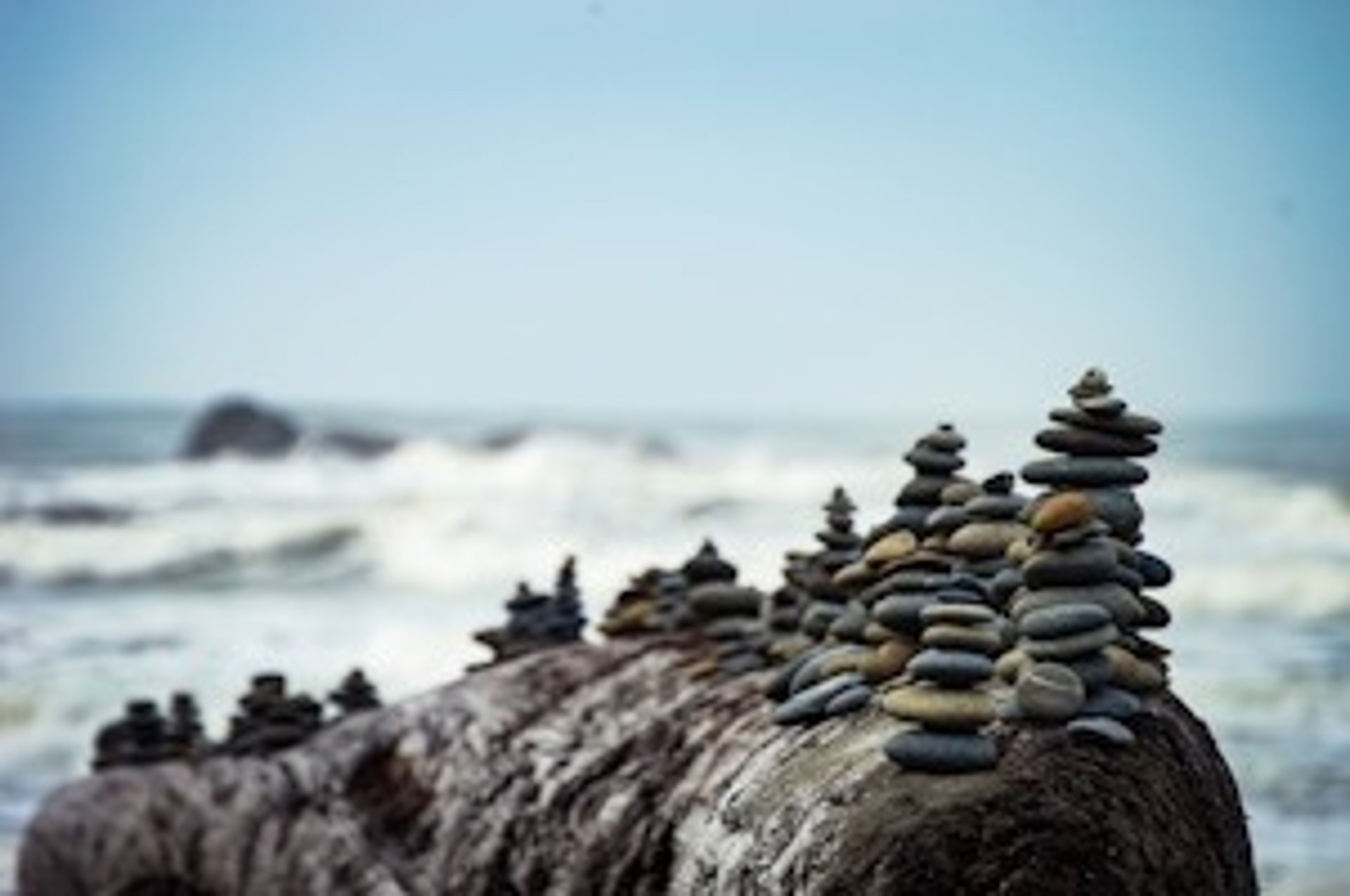 Stack of balanced stones on a rocky shore.