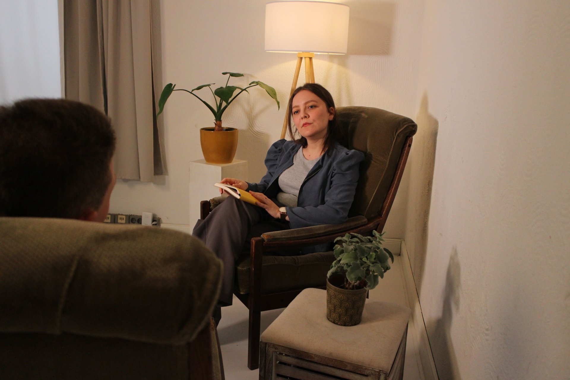 a consultant sitting on a chair and listening to her consultee who is sitting across her