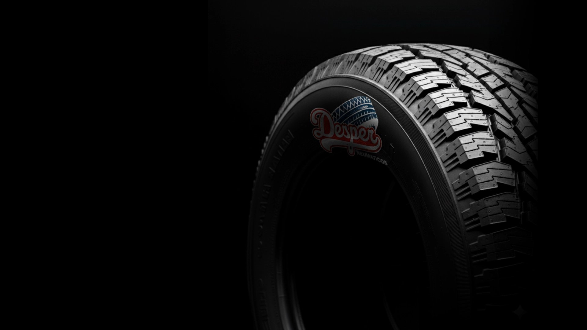 Neumático con el logo de "Desper Neumáticos" grabado en relieve en el costado, sobre un fondo negro, con el logo enfocado y e