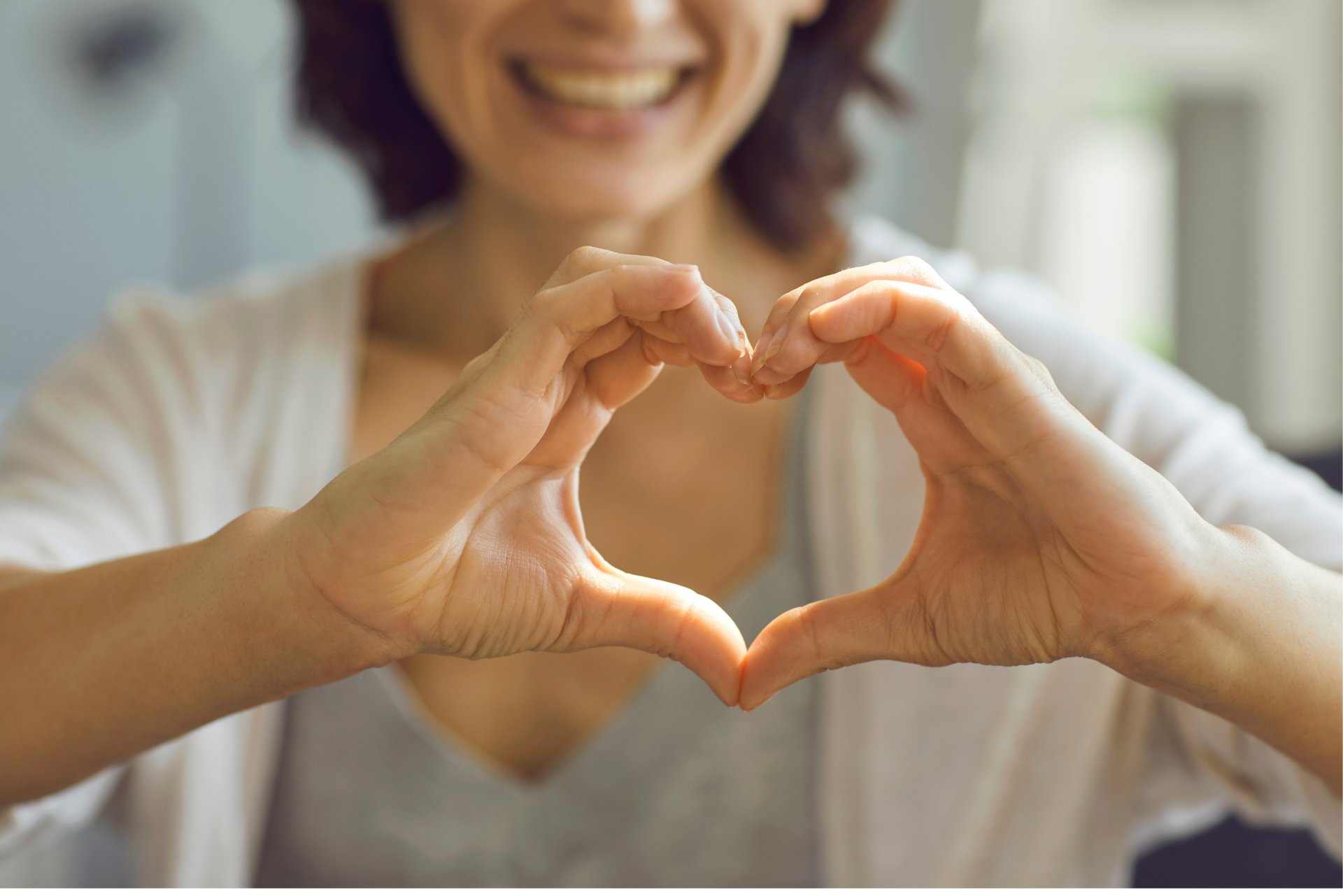 Mujer sonriendo haciendo con sus manos la forma de un corazón