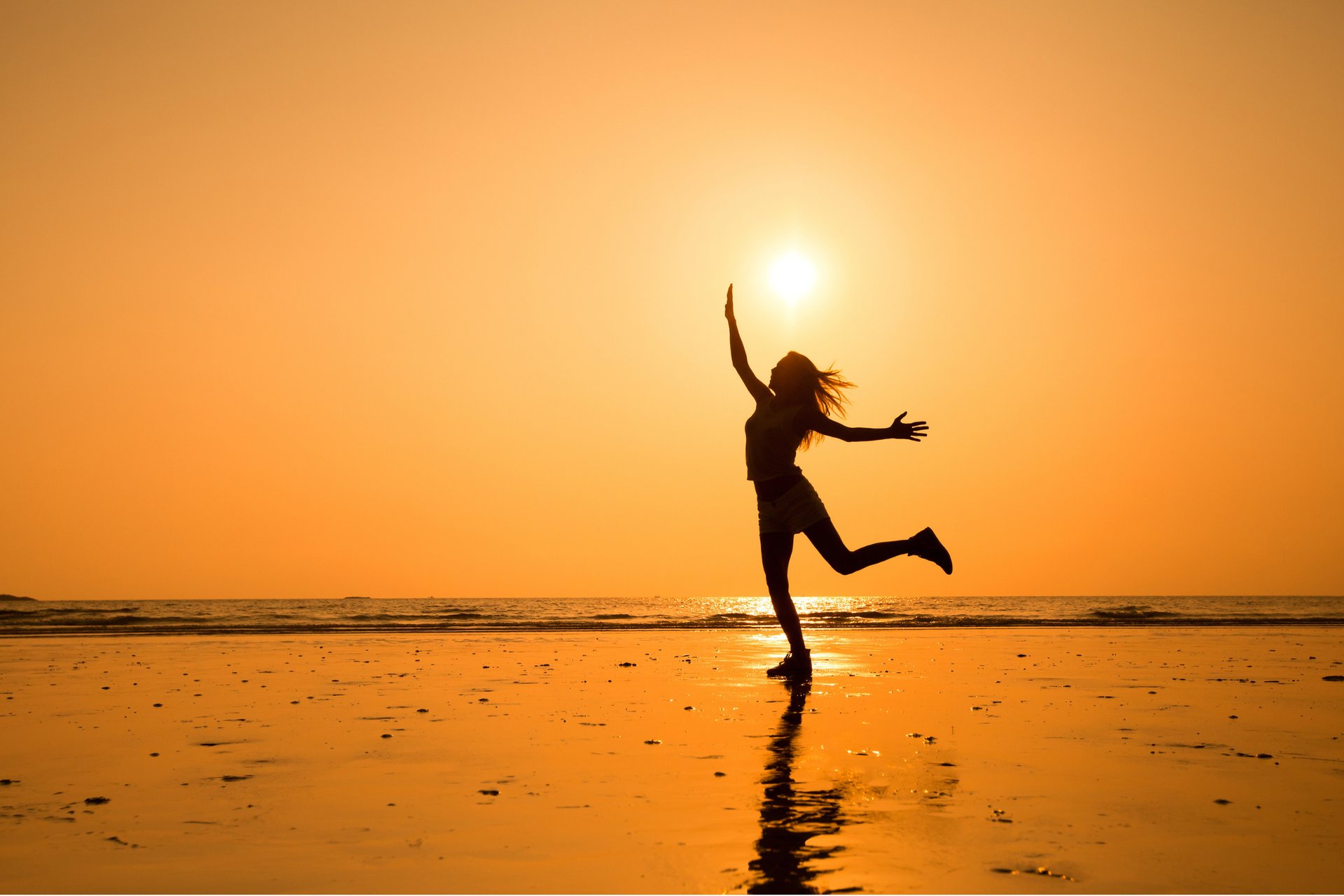 Chica bailando en el atardecer con el sol en la playa