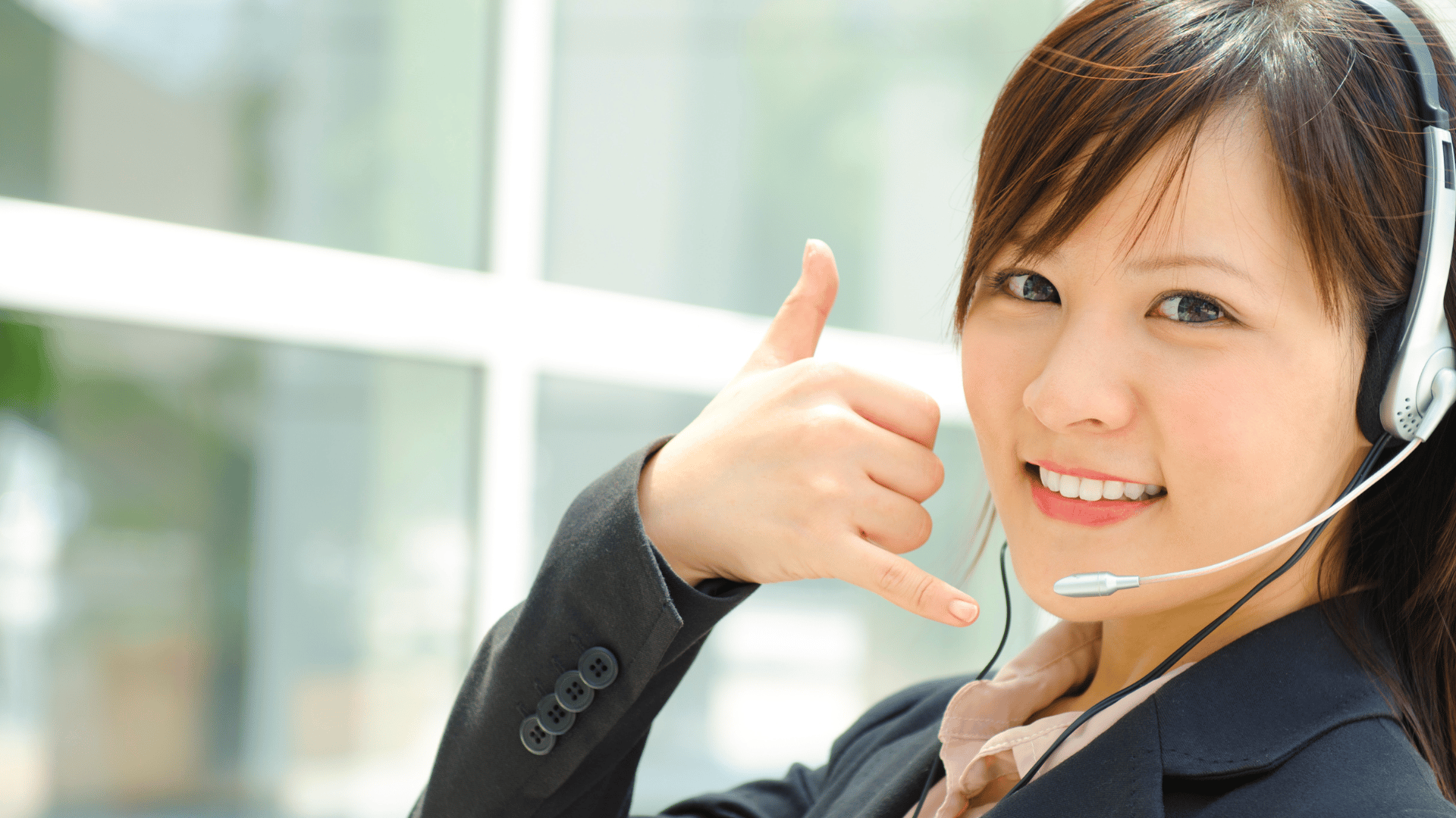 Woman on phone at desk with laptop and books.