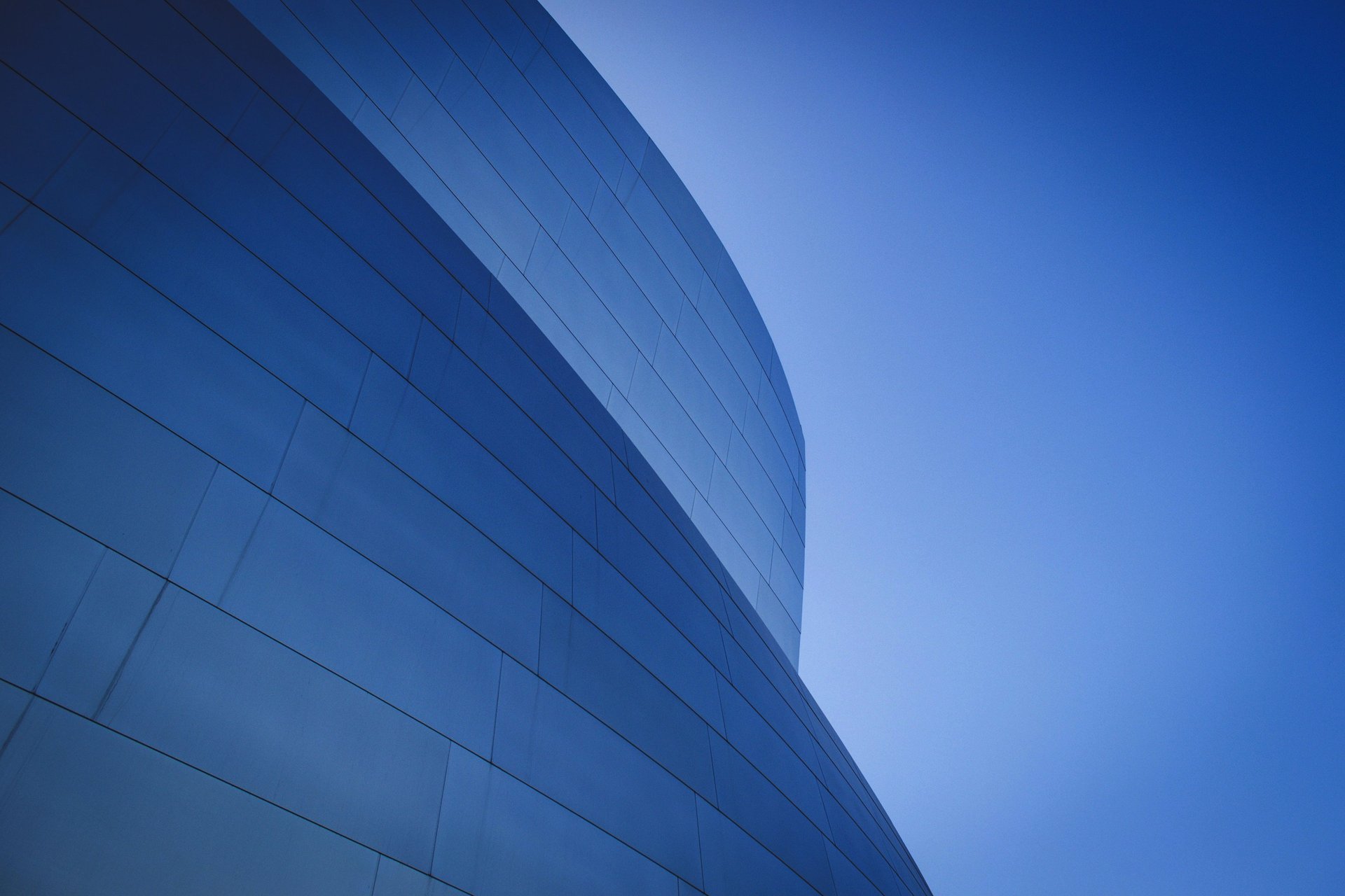 an abstract photo of a curved building with a blue sky in the background