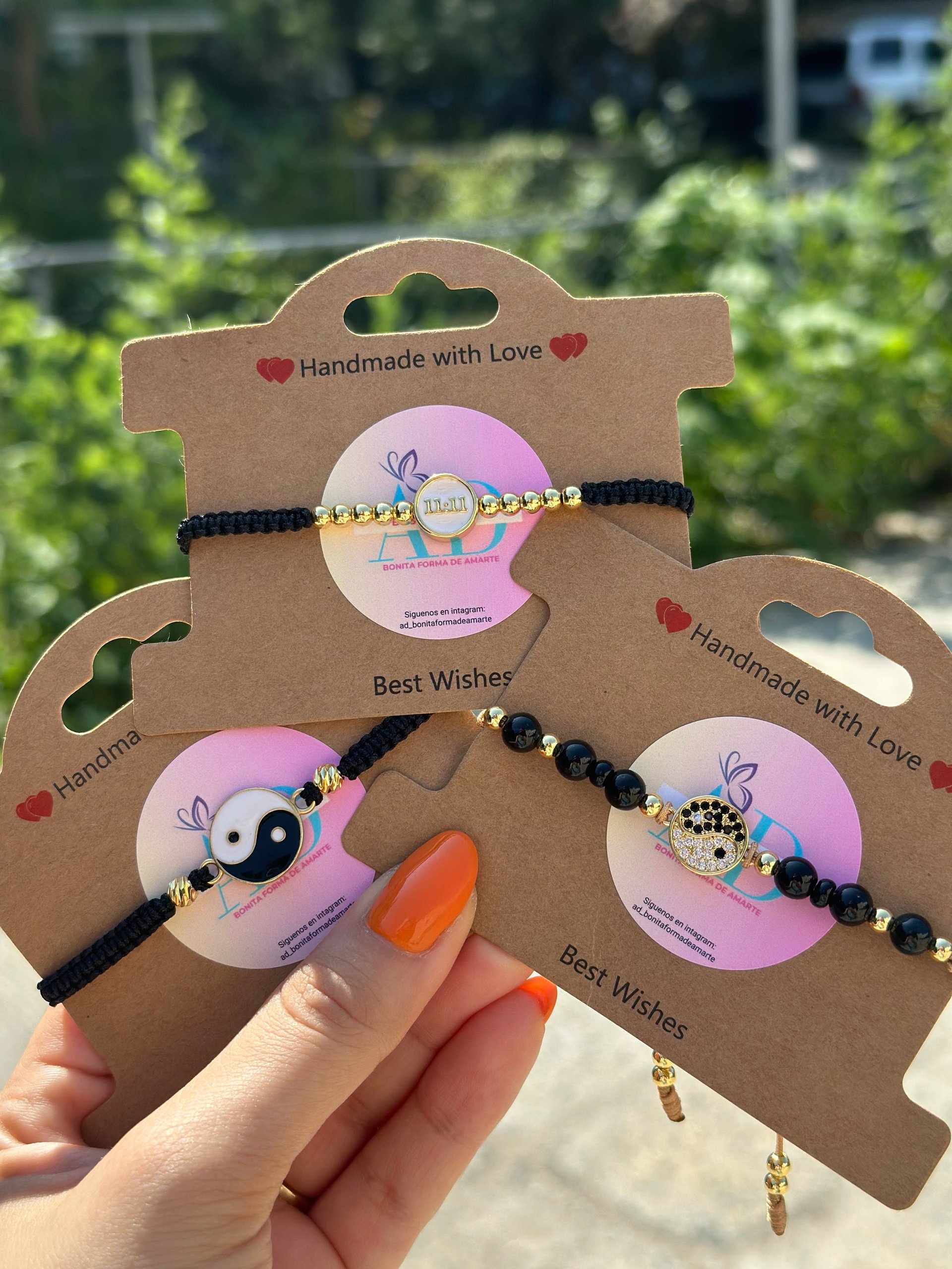 Tres diferentes pulseras tejidas a mano con fondo verde y sostenidas por una mano