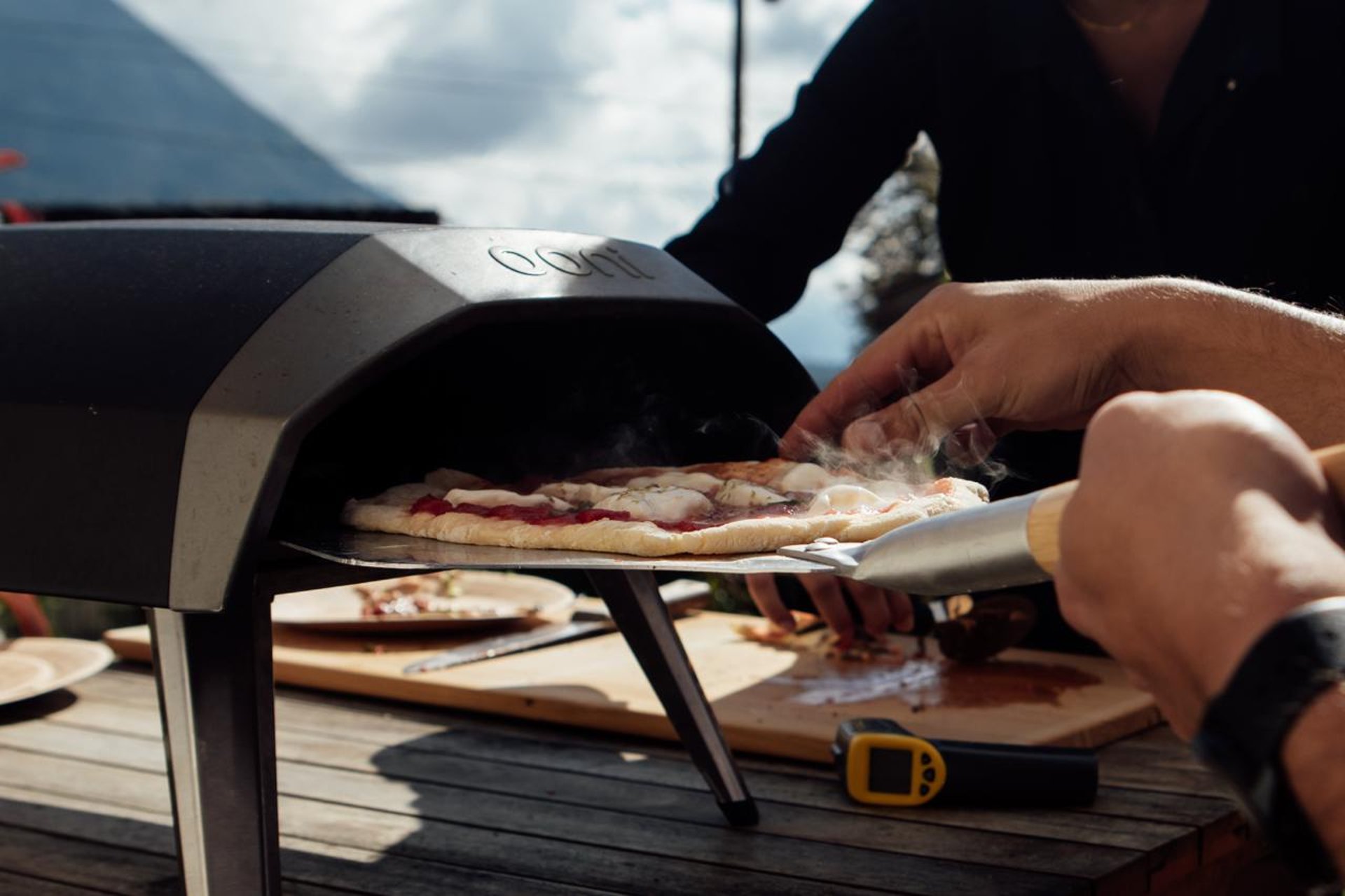 green grass covered mountain beside body of water under white clouds during daytime