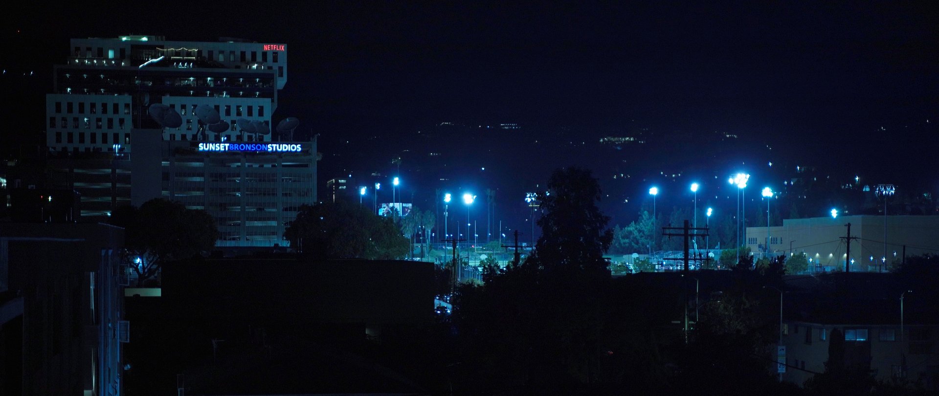 man in gray jacket and black backpack standing on green grass field near mountain during daytime