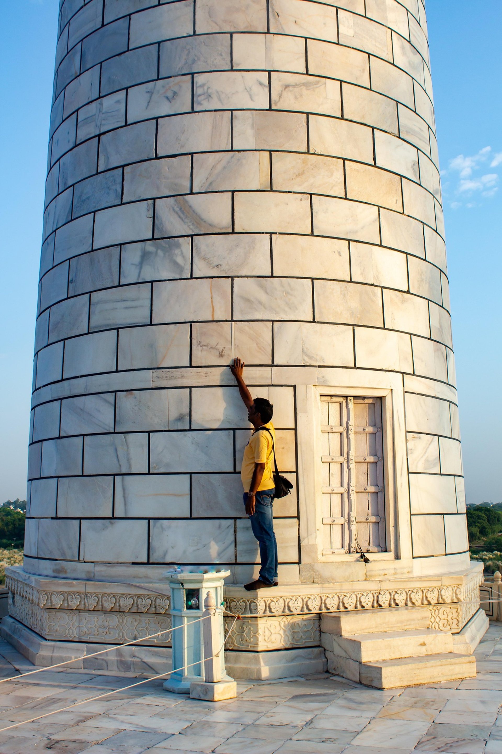 man in gray jacket and black backpack standing on green grass field near mountain during daytime