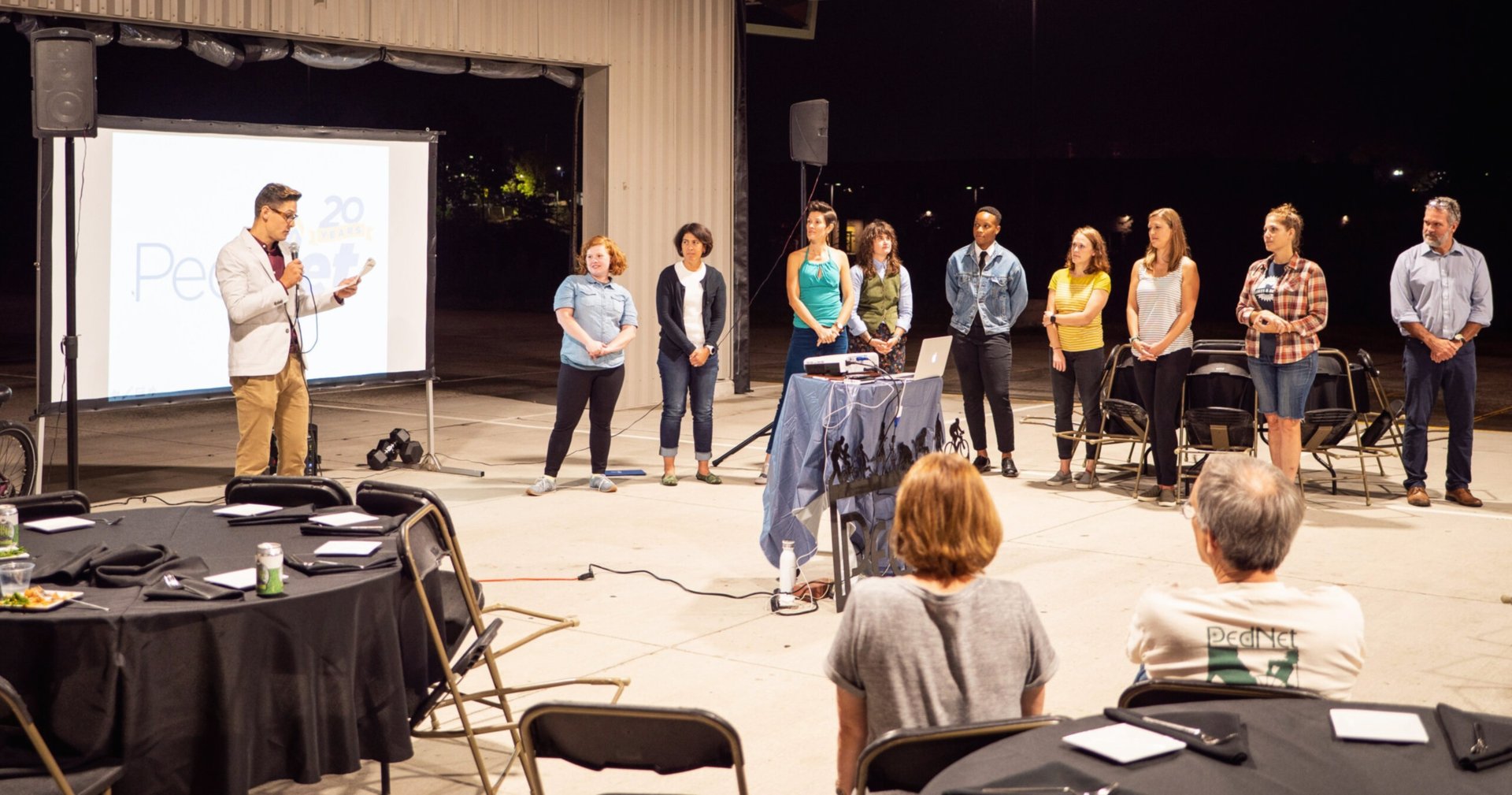 Staff members lined up in front of an audience, giving a presentation