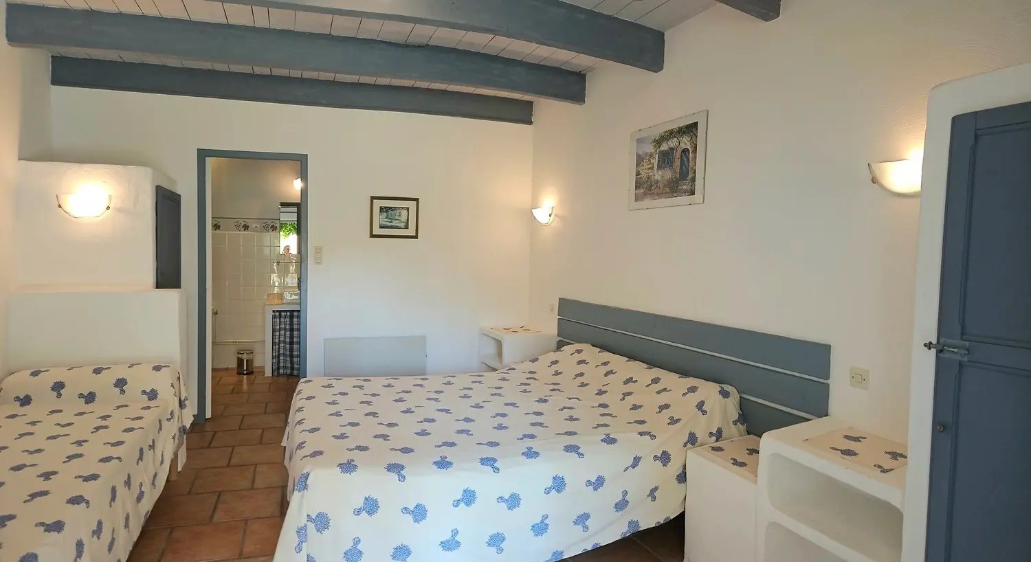 chambre romarin "la ramade" avec un grand lit et un petit lit, mur blanc, poutre et placard bleu 