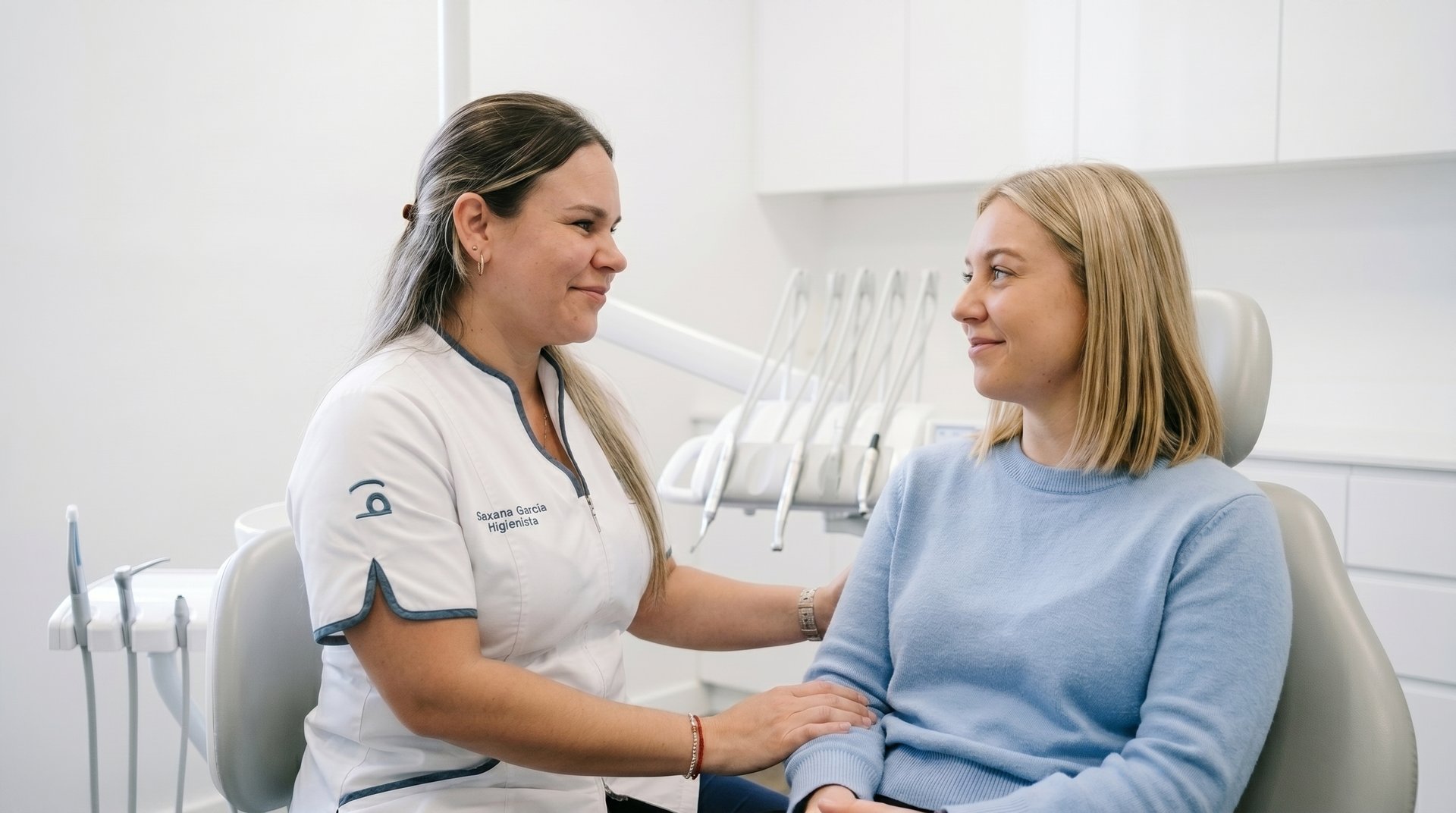 A friendly dental hygienist consulting with a patient in a modern dental office chair.