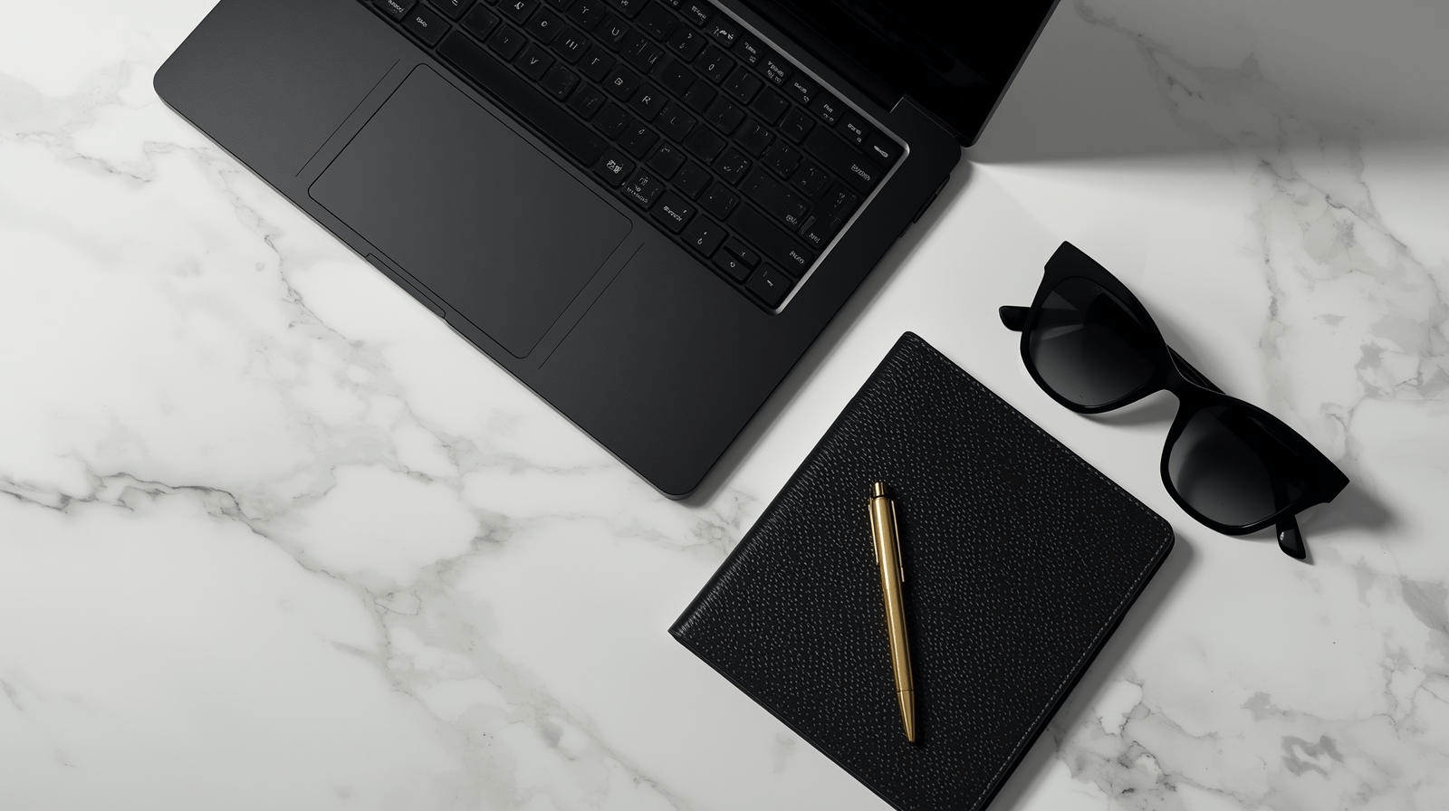 a laptop computer and a notebook with a pen and glasses