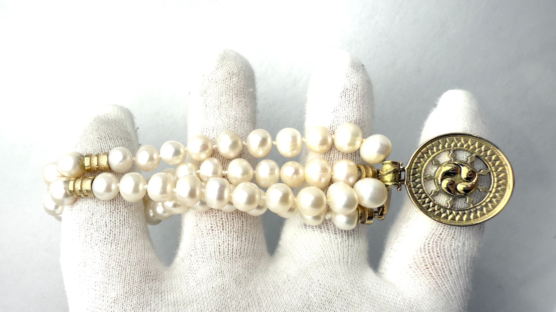a woman's hand holding a bracelet with a gold coin
