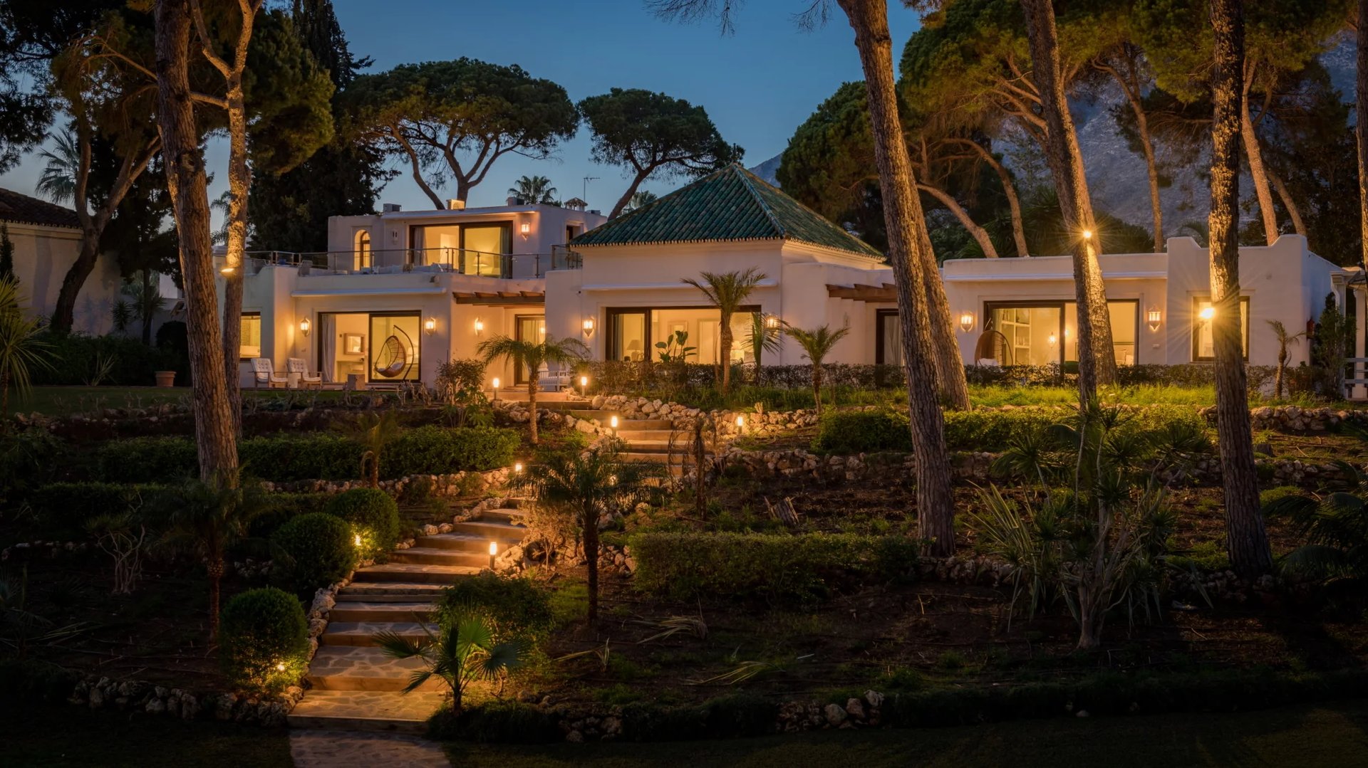 Evening exterior view with landscaped gardens and illuminated façade