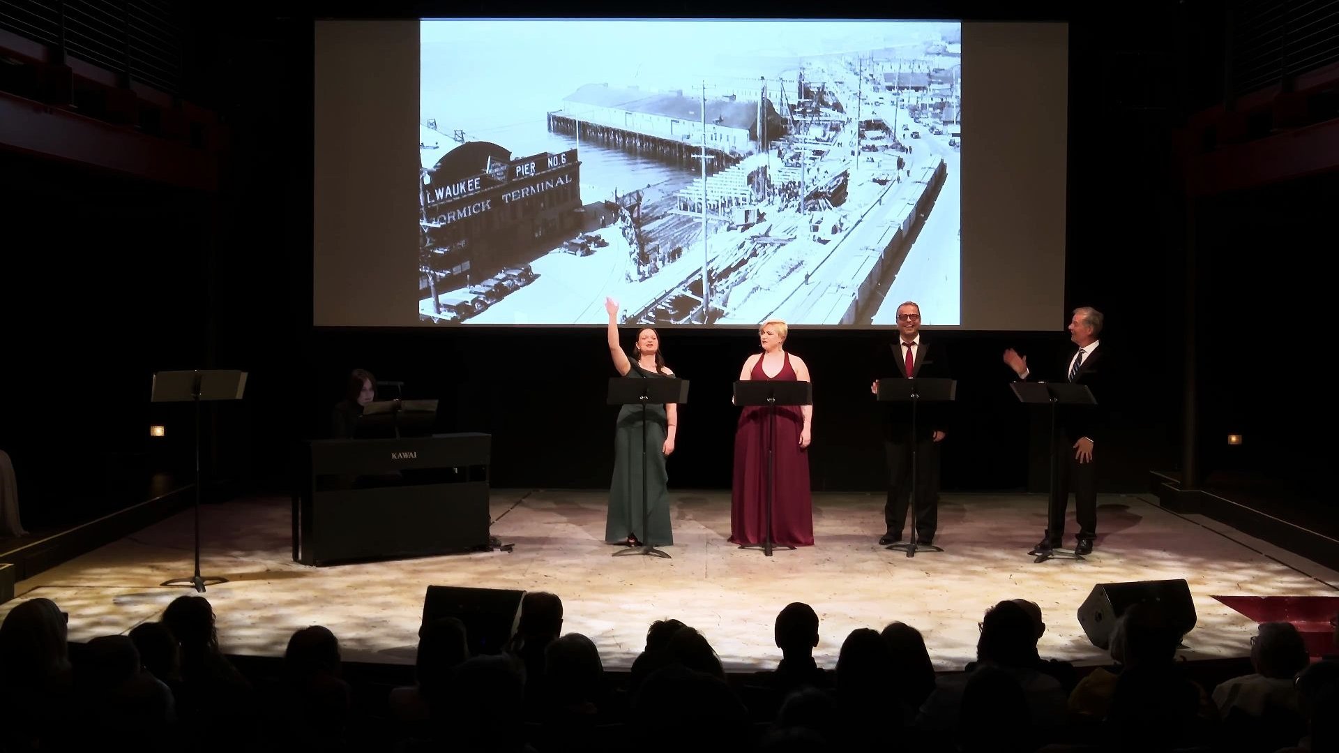 Singers performing on stage with a pianist & vintage backdrop projection of docks at a city Port.