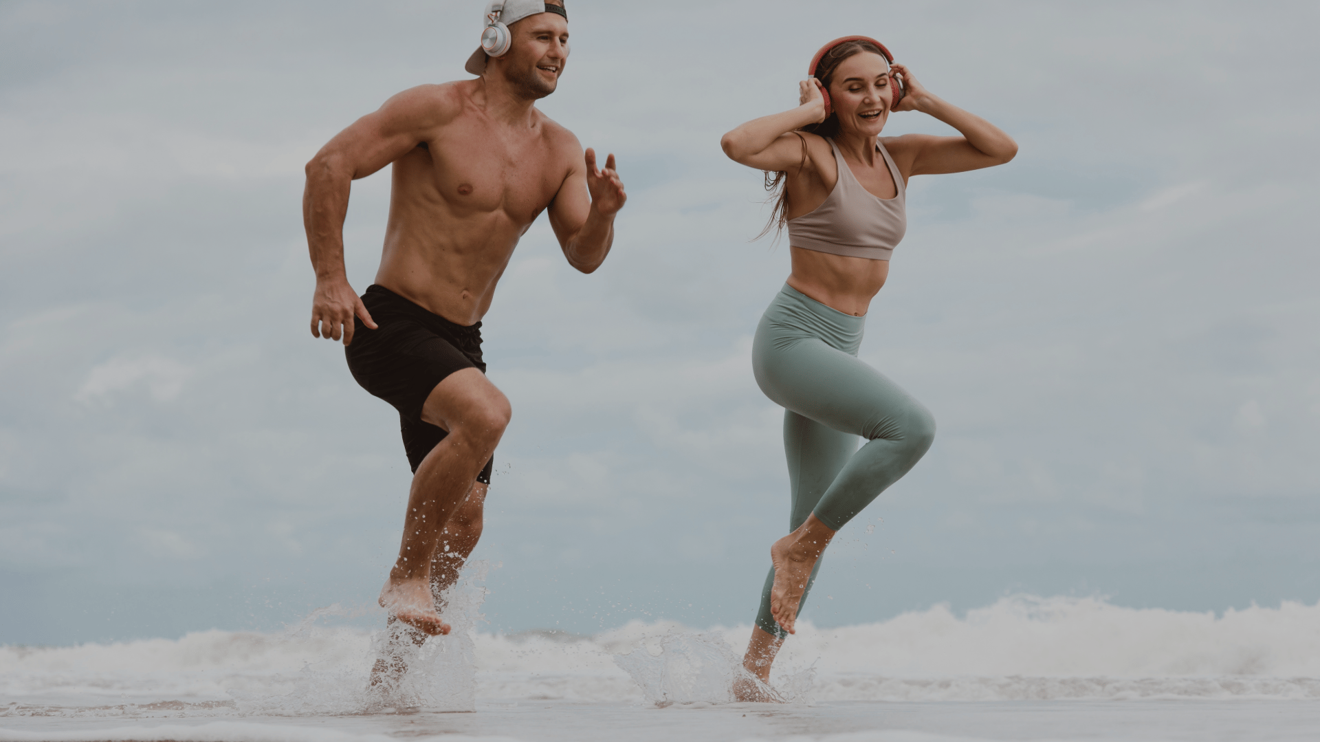 a man and woman running in the ocean